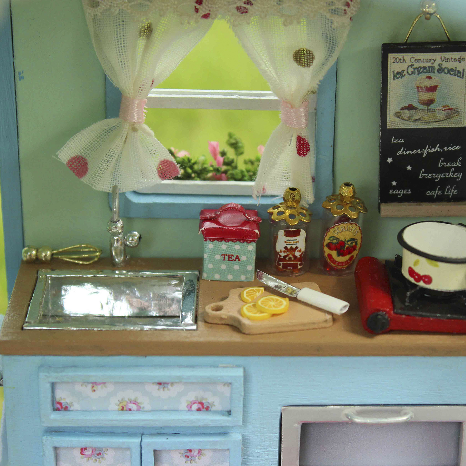 Scena di cucina in miniatura con lavello, fornello, cibo e finestra.