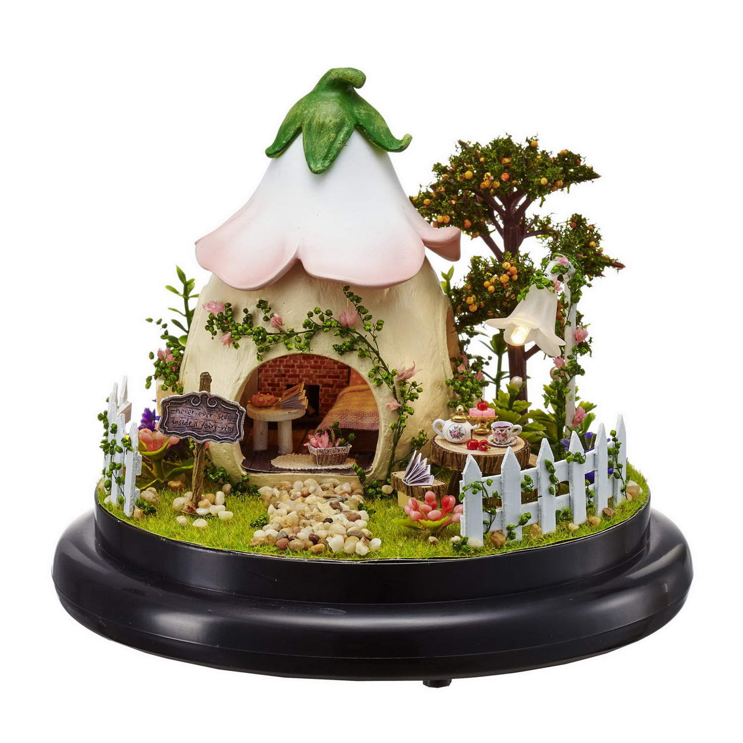 Mini casa delle fate con tetto rosa e bianco, albero da frutto e recinzione da giardino.