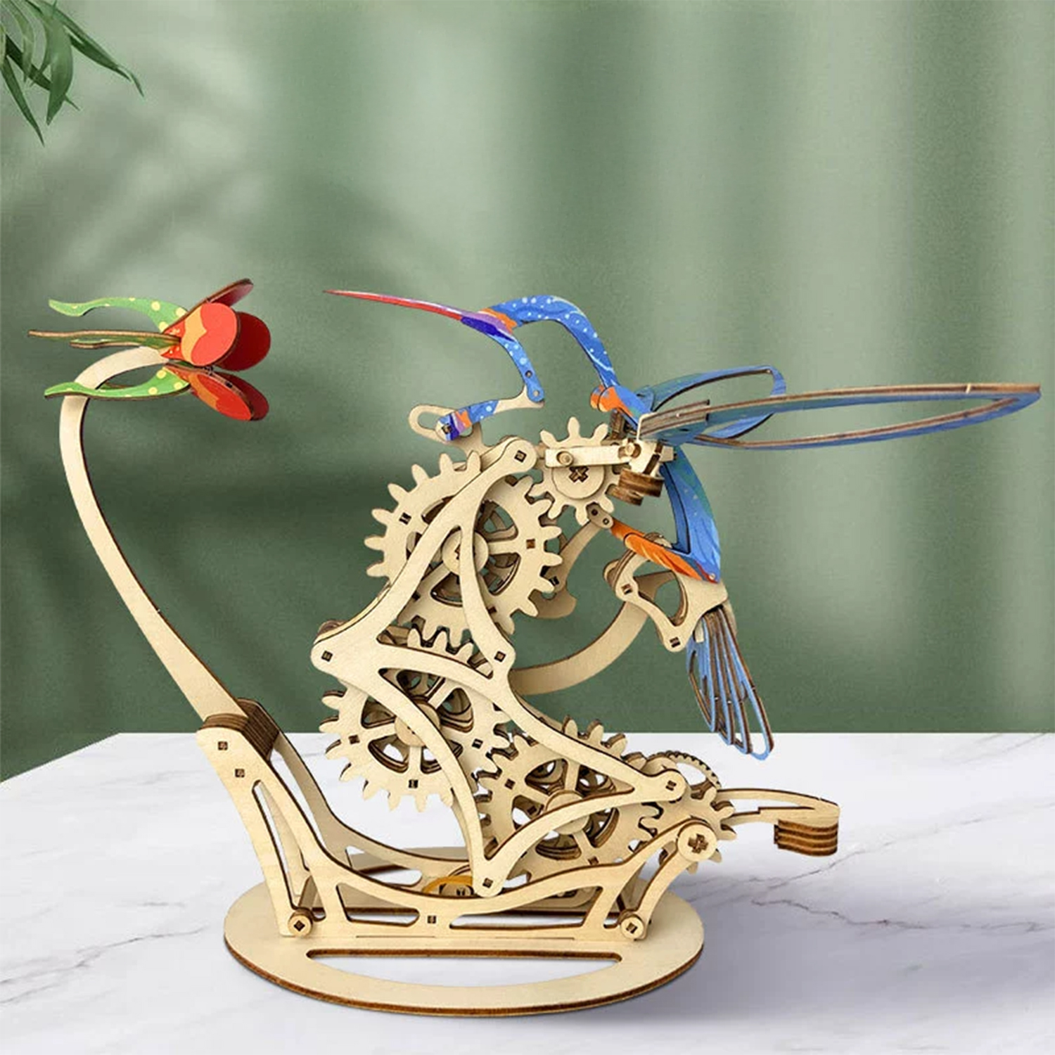 Modello in legno di un colibrì con ingranaggi e un fiore.