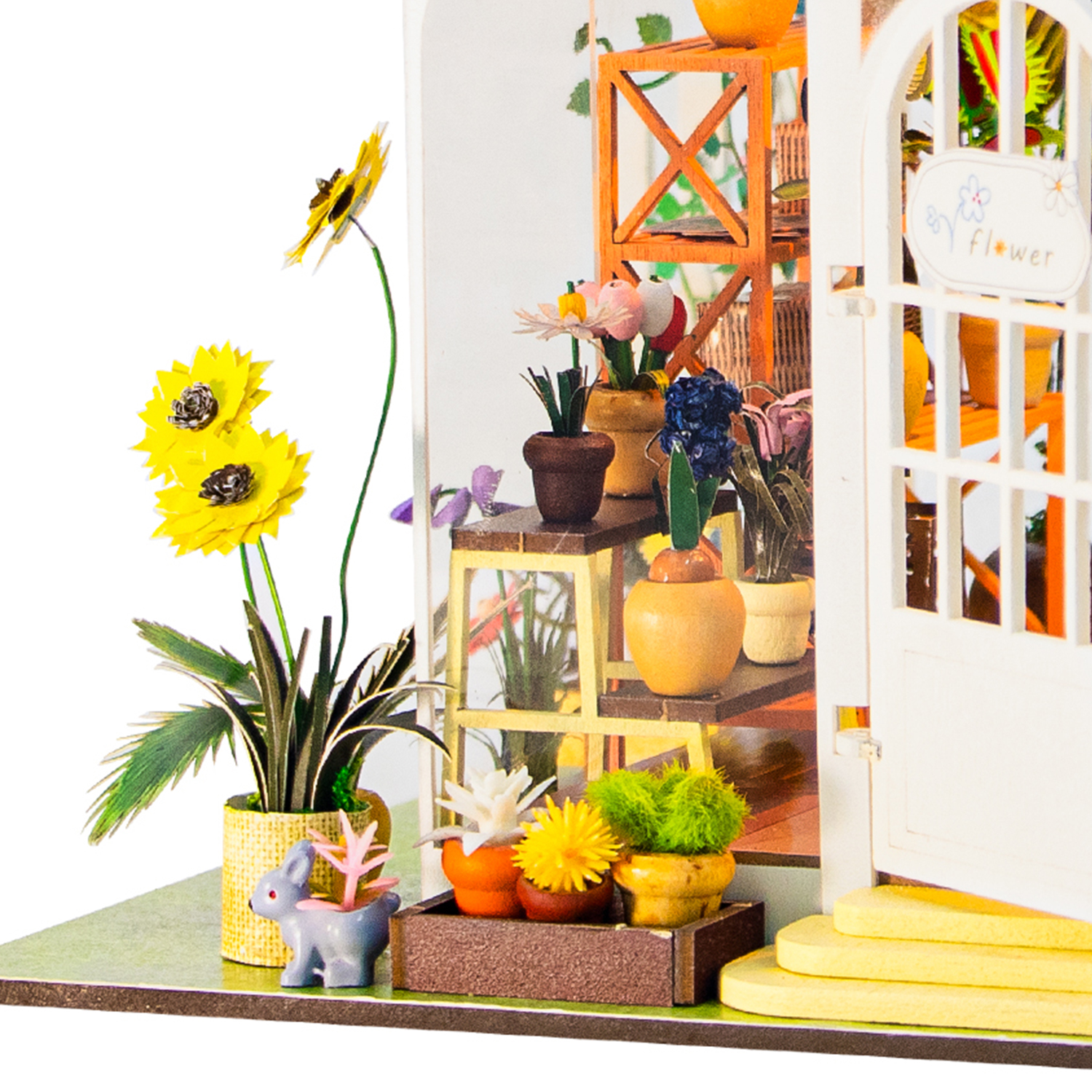 Negozio di fiori in miniatura con girasoli gialli, piante e statuetta di coniglio.