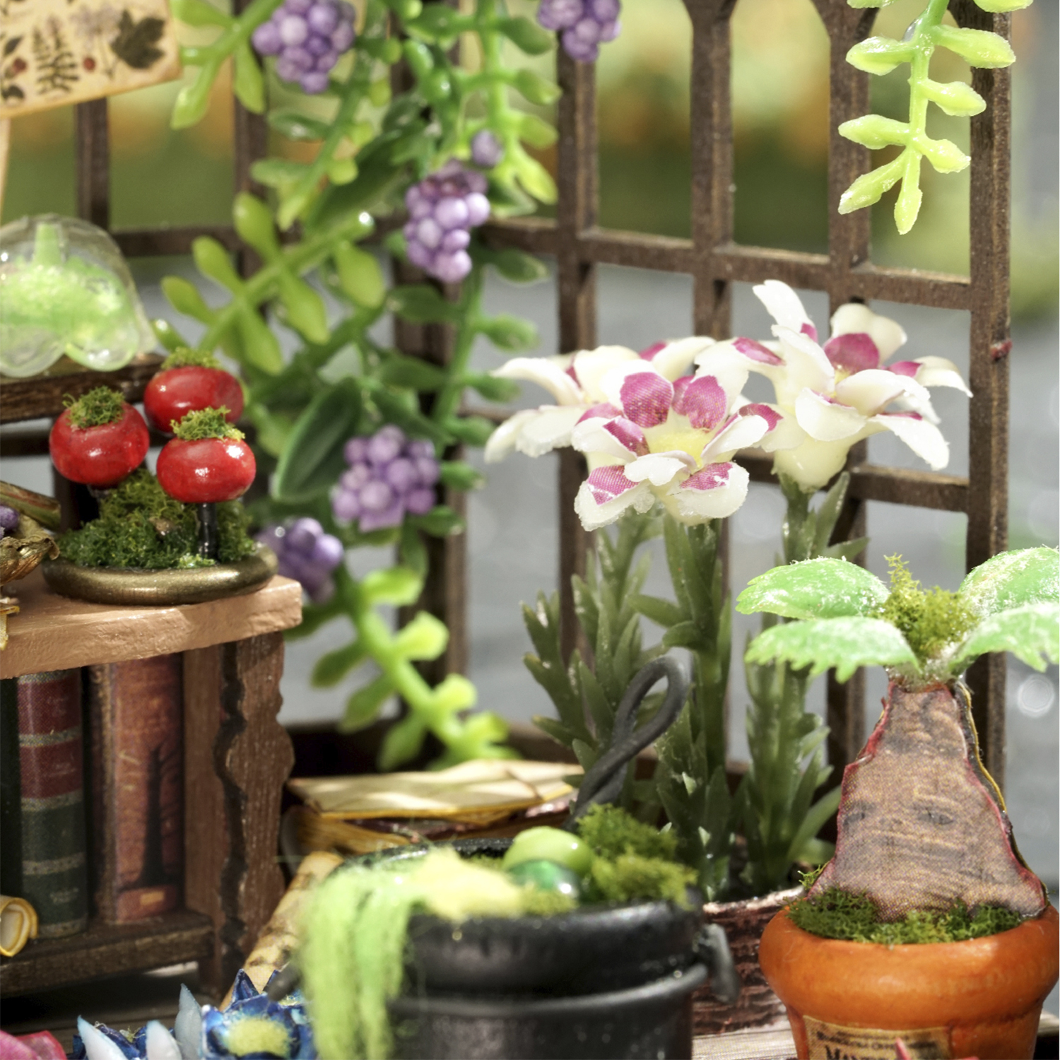 Giardino in miniatura con fiori, bacche, libri e un vaso.