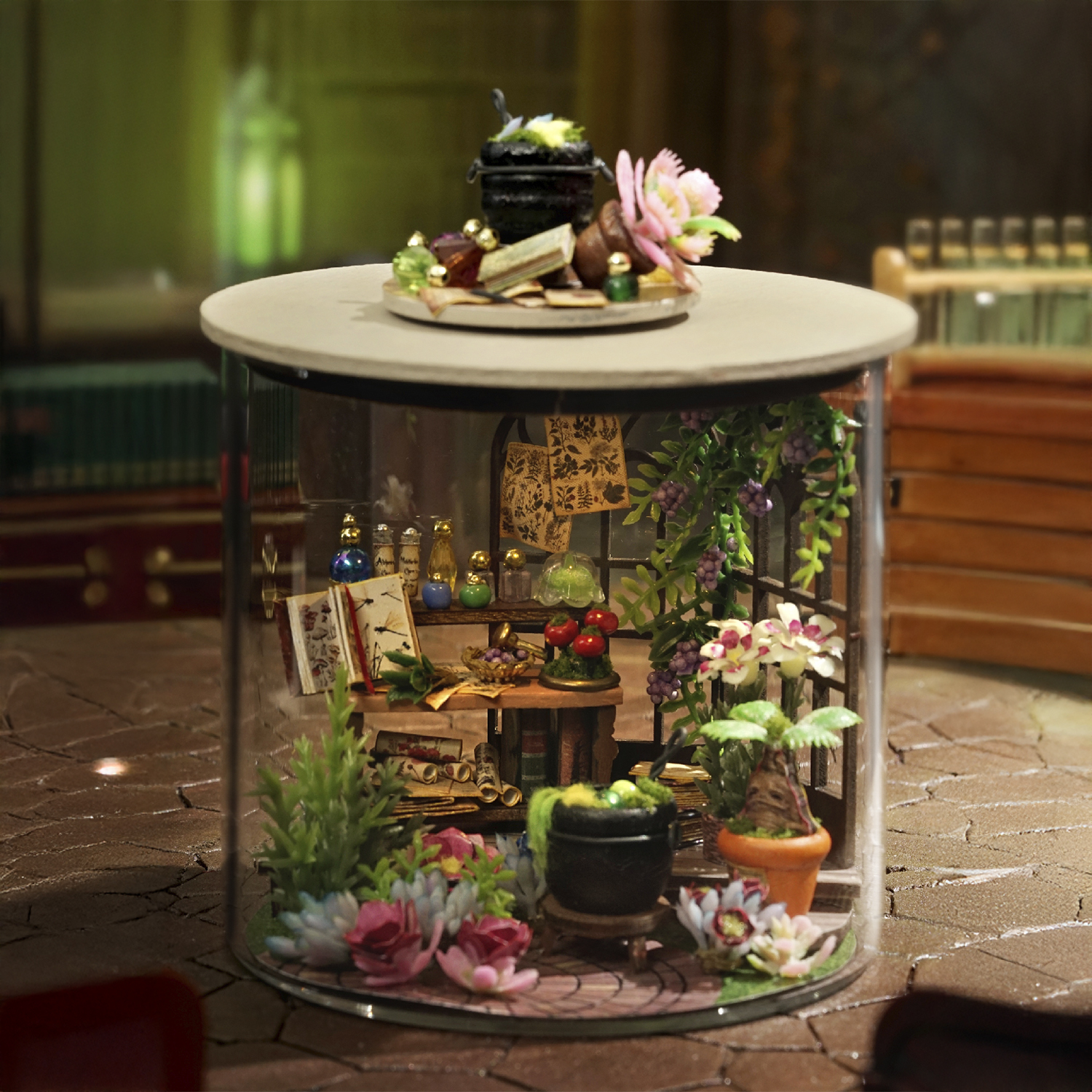 Laboratorio di strega in miniatura con calderone, bottiglie, libri e fiori.