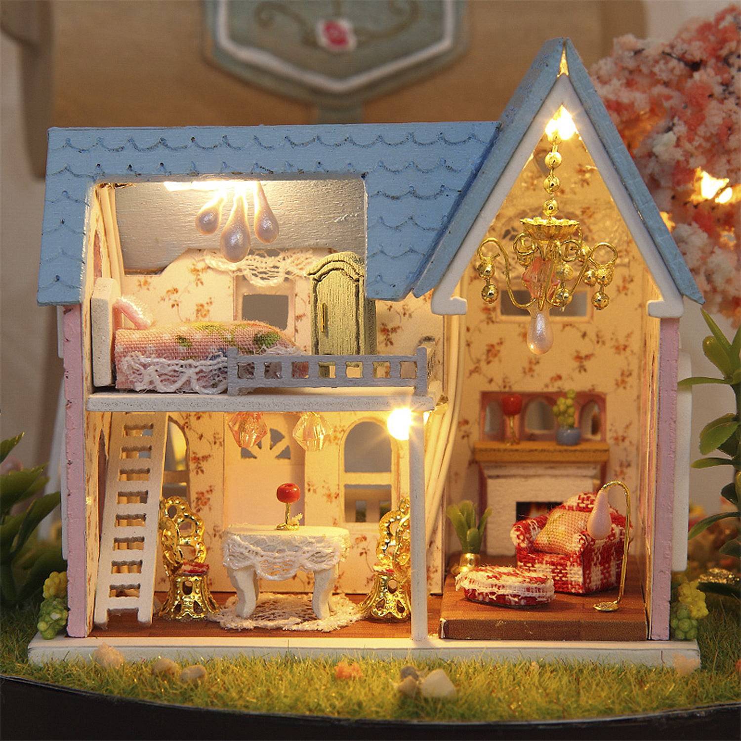 Una dettagliata casa delle bambole in miniatura con mobili, luci e decorazioni, su base erbosa.