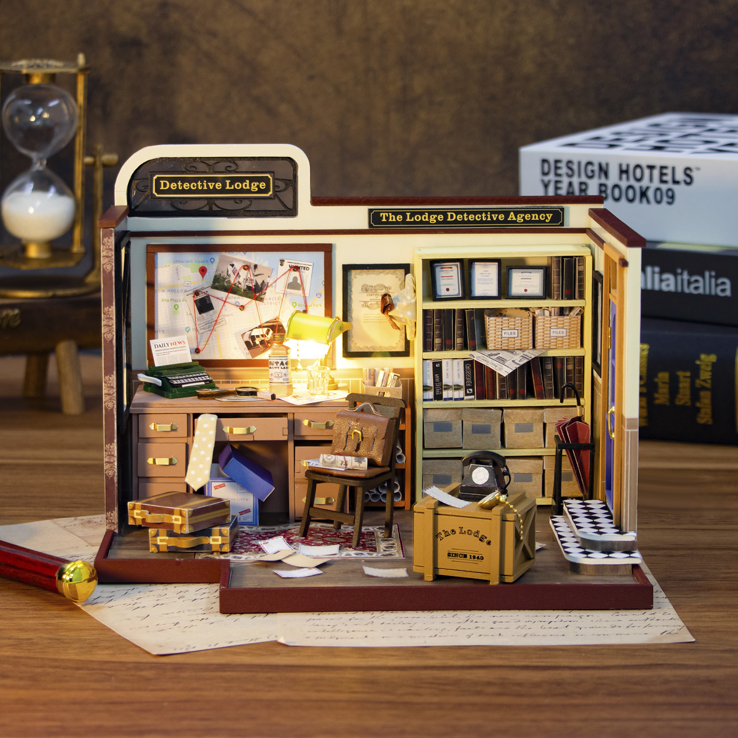 Ufficio investigativo in miniatura con scrivania, mappa, librerie e scatole.