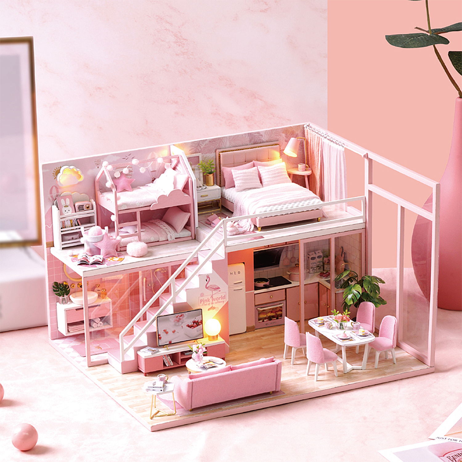 Una casa delle bambole in miniatura rosa con più stanze, tra cui camere da letto, soggiorno e cucina.