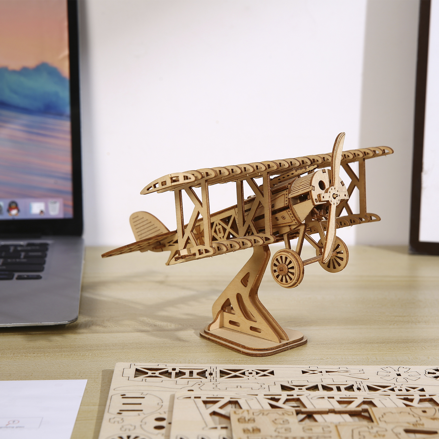 Un modello di aeroplano in legno su un supporto, accanto a un laptop.
