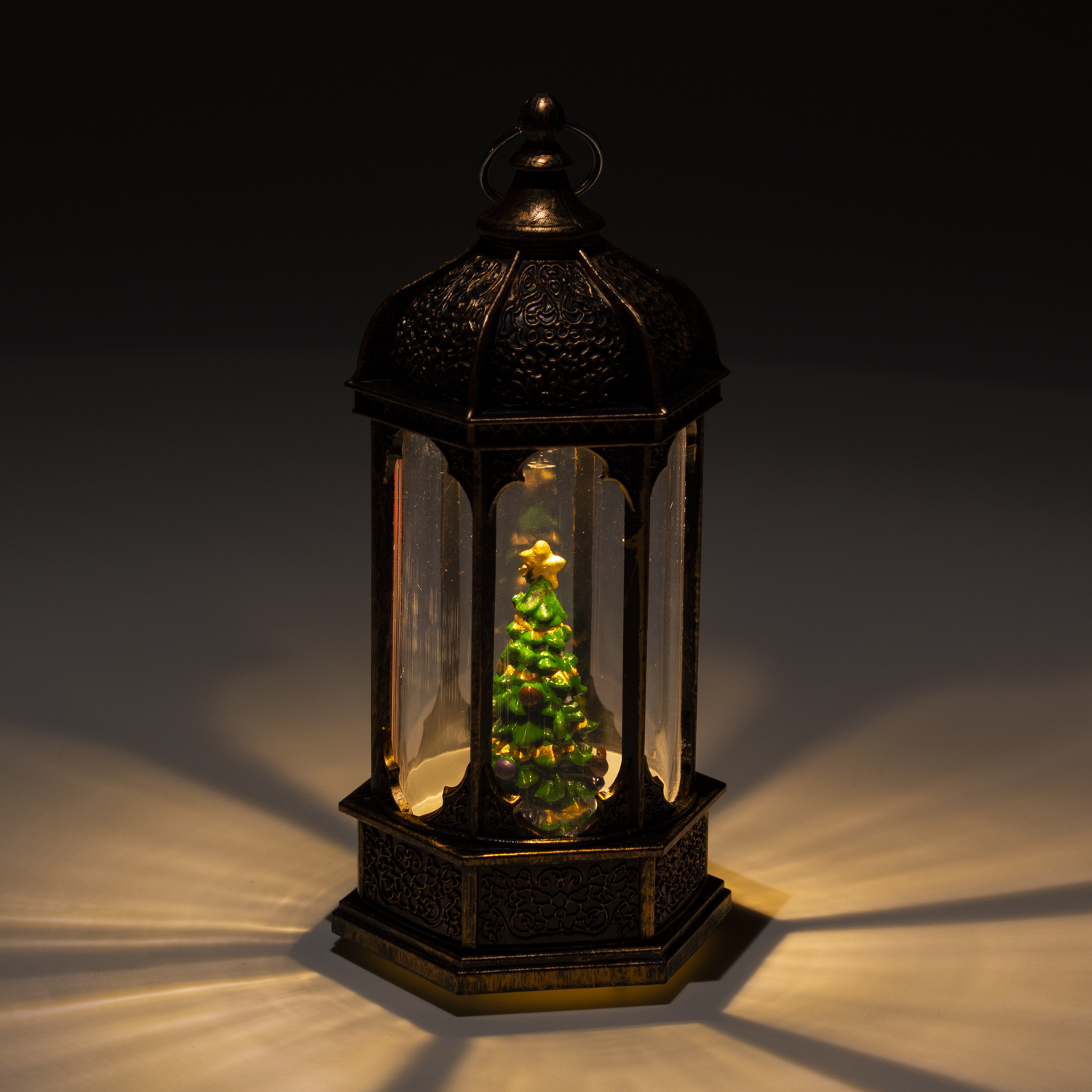 Lanterna marrone scuro con albero di Natale all'interno, illuminata.