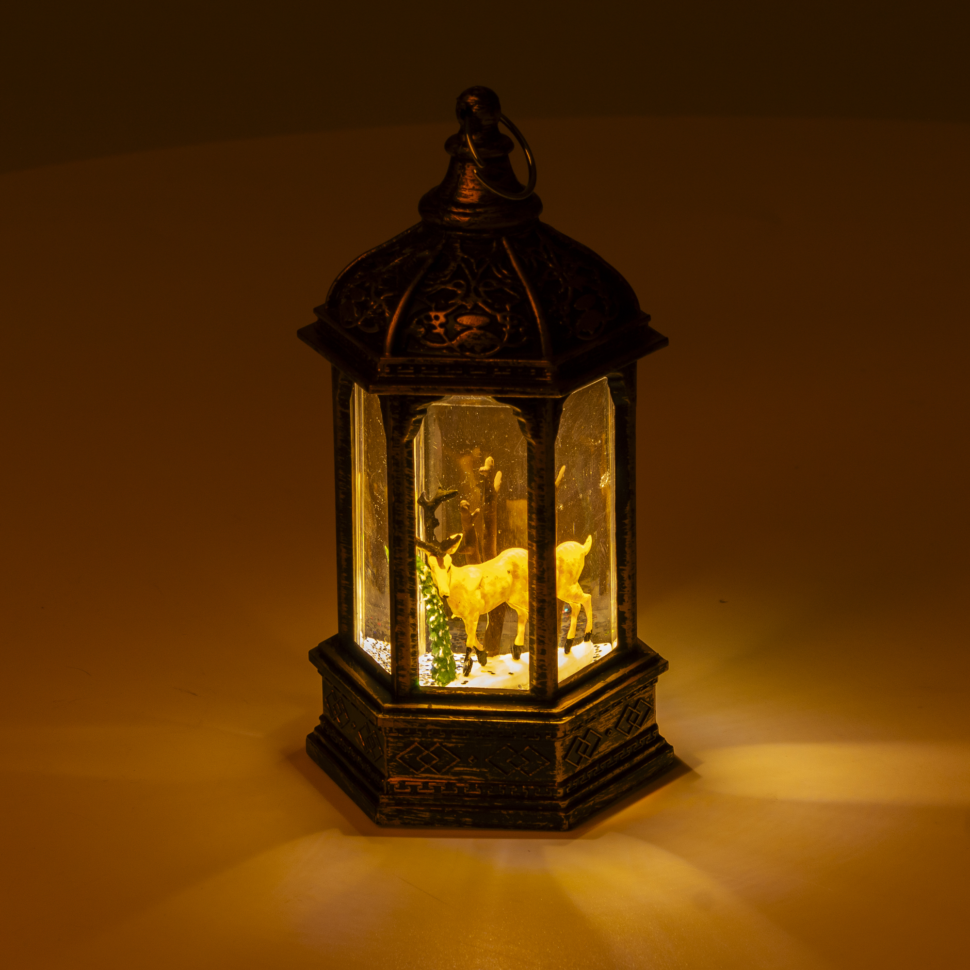 Una lanterna accesa con una statuetta di cervo all'interno, che proietta una calda luce.