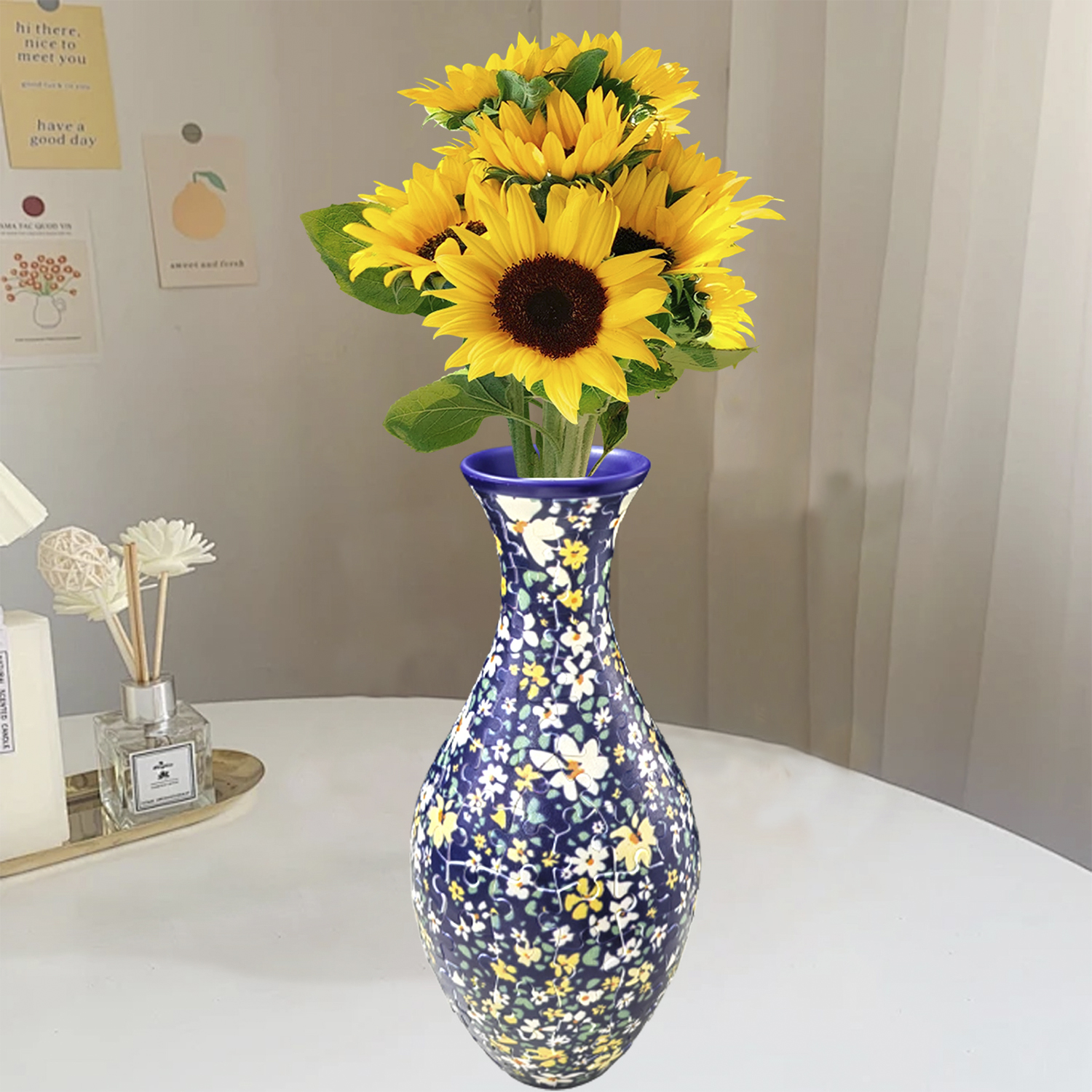 Un vaso floreale con girasoli è su un tavolo. Ci sono appunti sul muro.