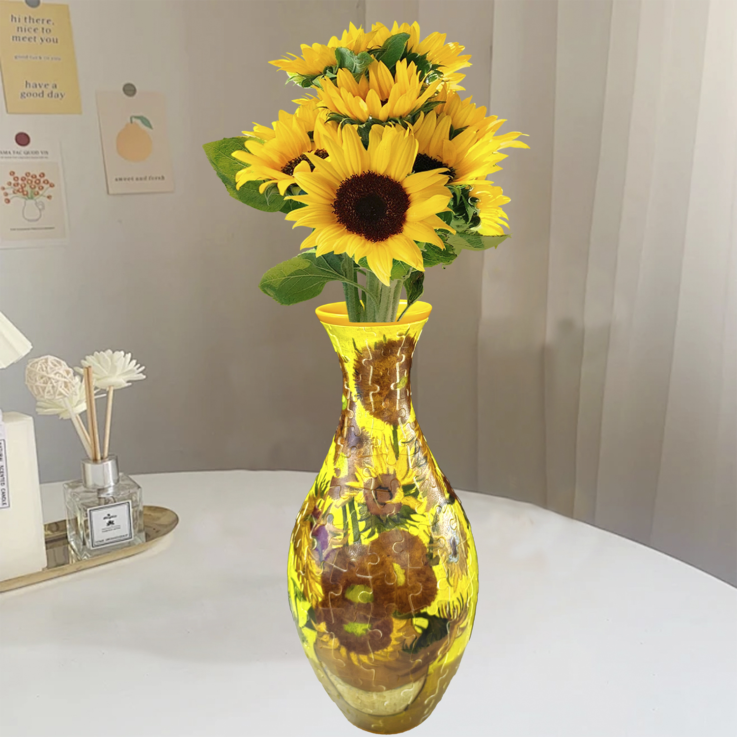 Un mazzo di girasoli in un vaso giallo con motivo a puzzle. Candela e diffusore nelle vicinanze.