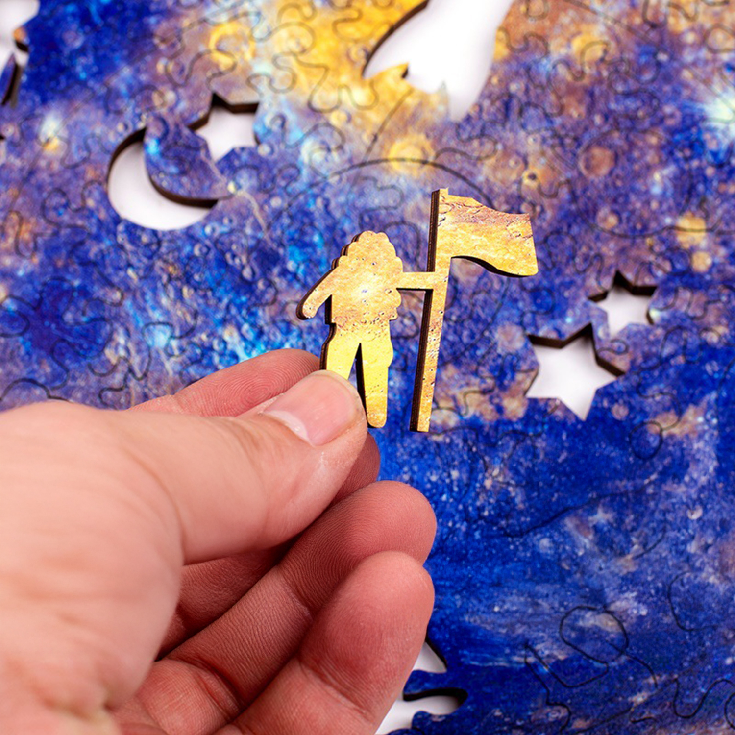Un dito tiene una figura di astronauta di legno con una bandiera contro un puzzle a tema spaziale.