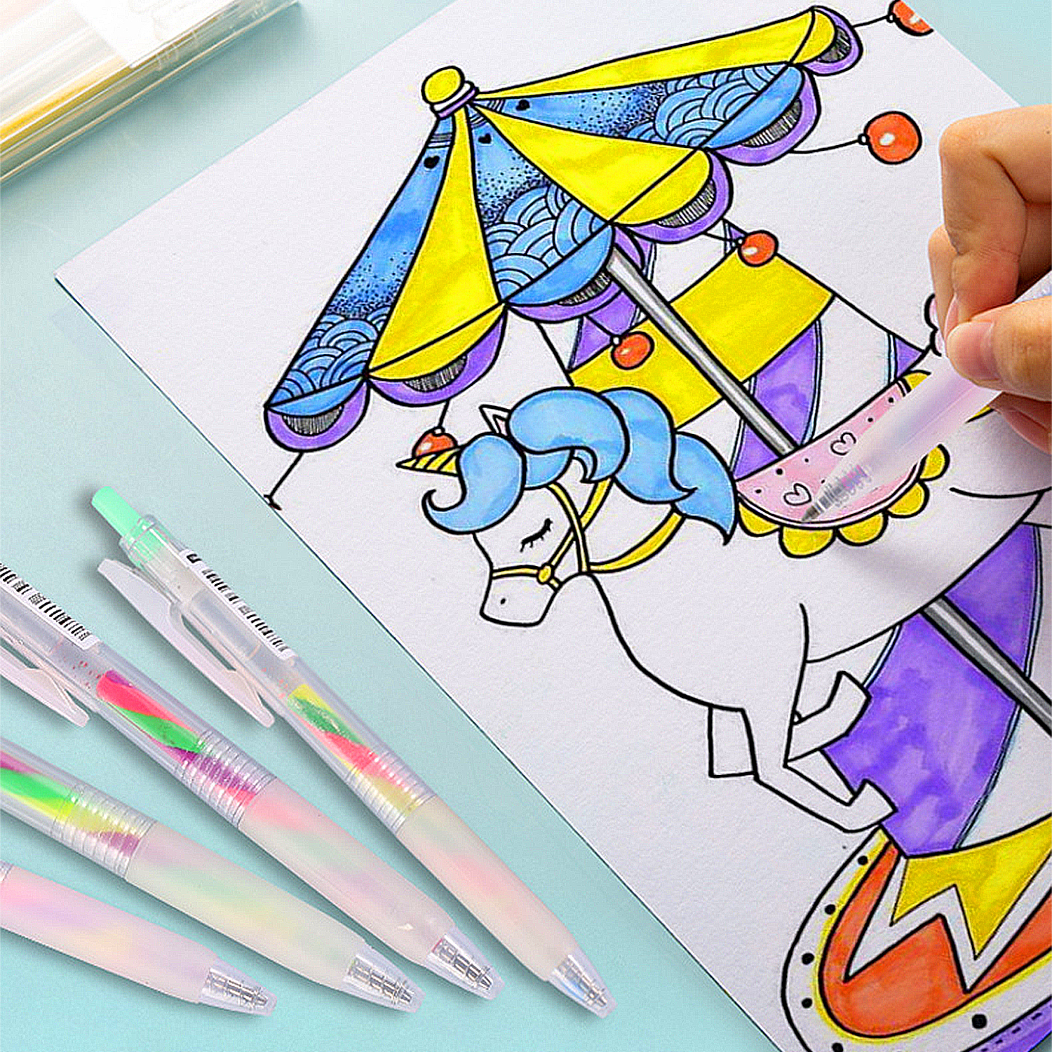 Un juego de bolígrafos junto a un dibujo de un unicornio en un carrusel.