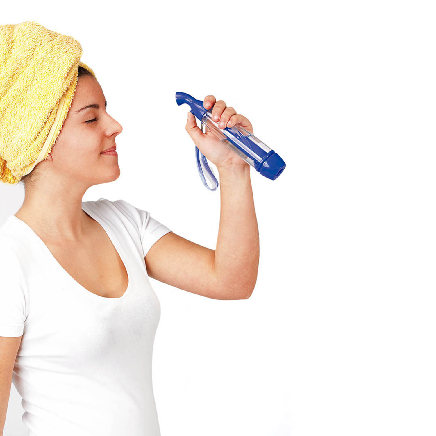 Mujer con toalla amarilla en la cabeza se rocía la cara con agua.