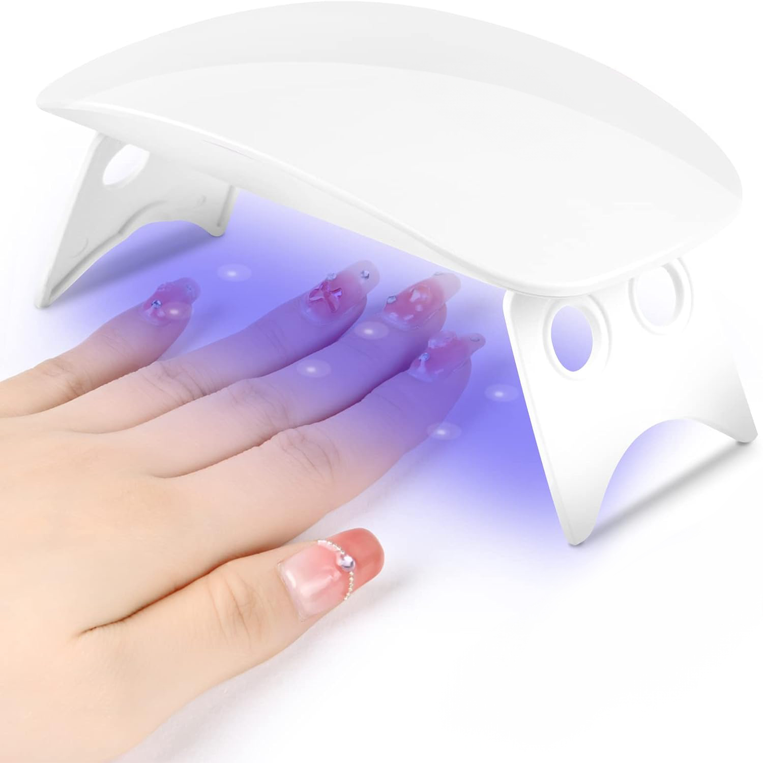 Una mano con uñas decoradas se seca bajo una lámpara UV blanca.