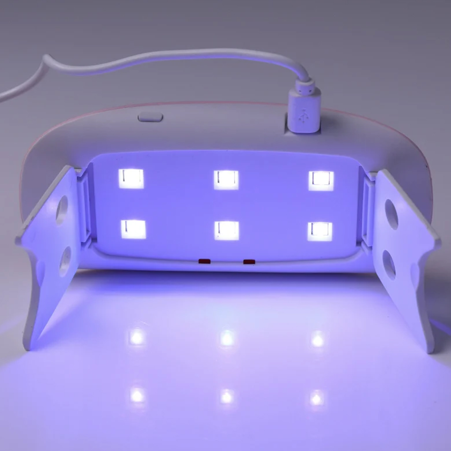 Una lámpara UV para uñas blanca con laterales abiertos y seis luces LED azules.
