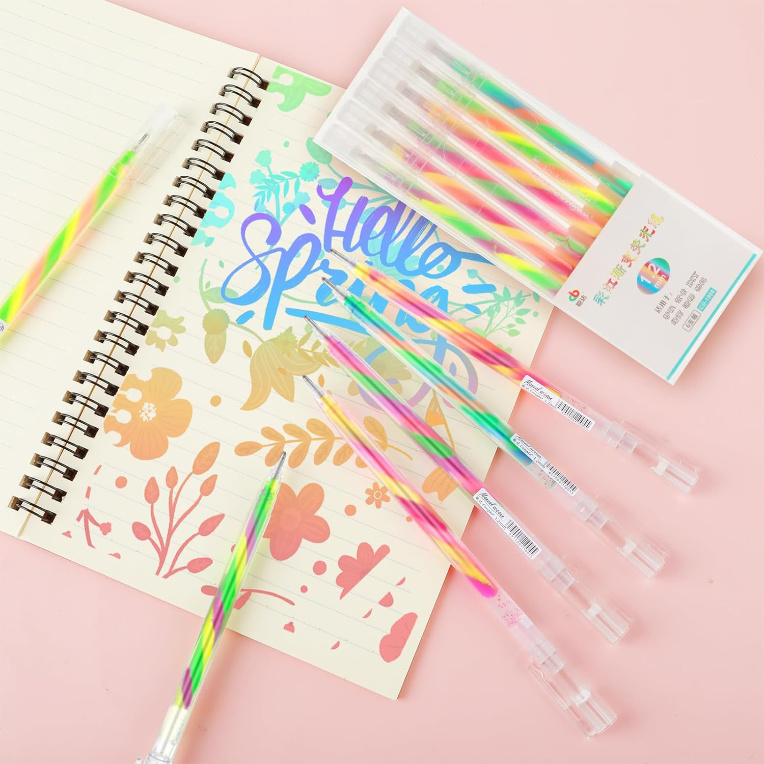 Bolígrafos espirales de colores junto a un cuaderno con diseños florales.