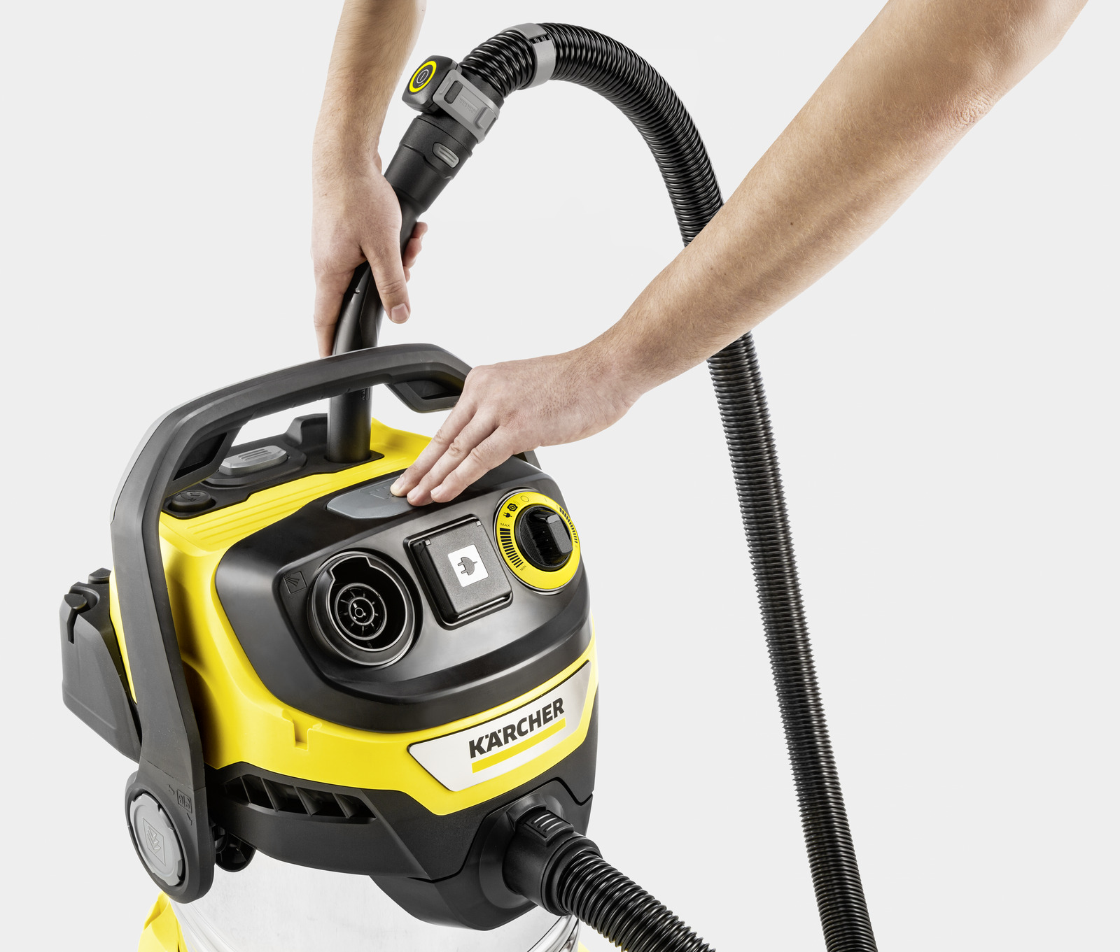 Persona collega il tubo all'aspirapolvere Karcher giallo. Mani che azionano.