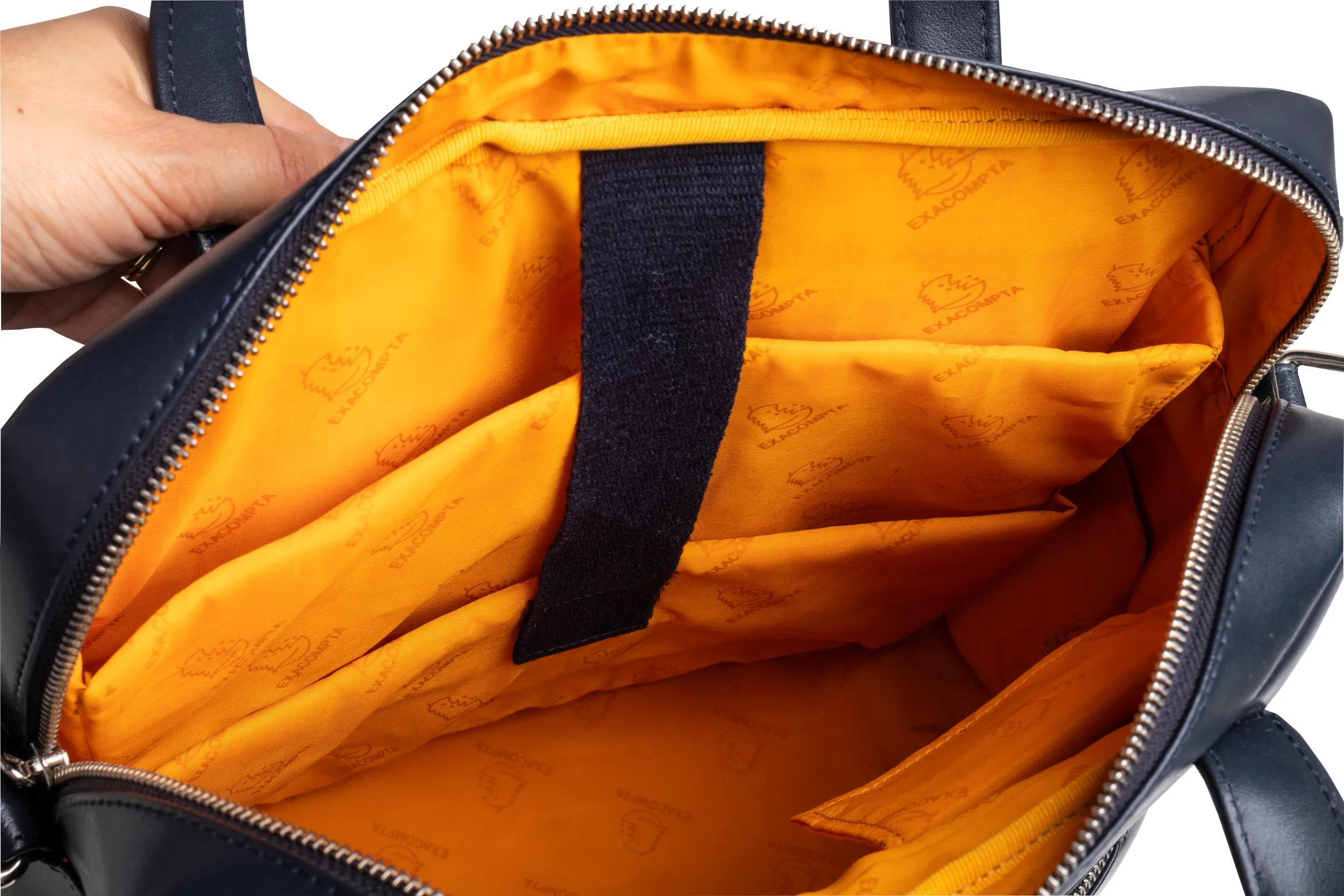 Bolso azul oscuro con forro naranja, estampado con logo. Vista interior.
