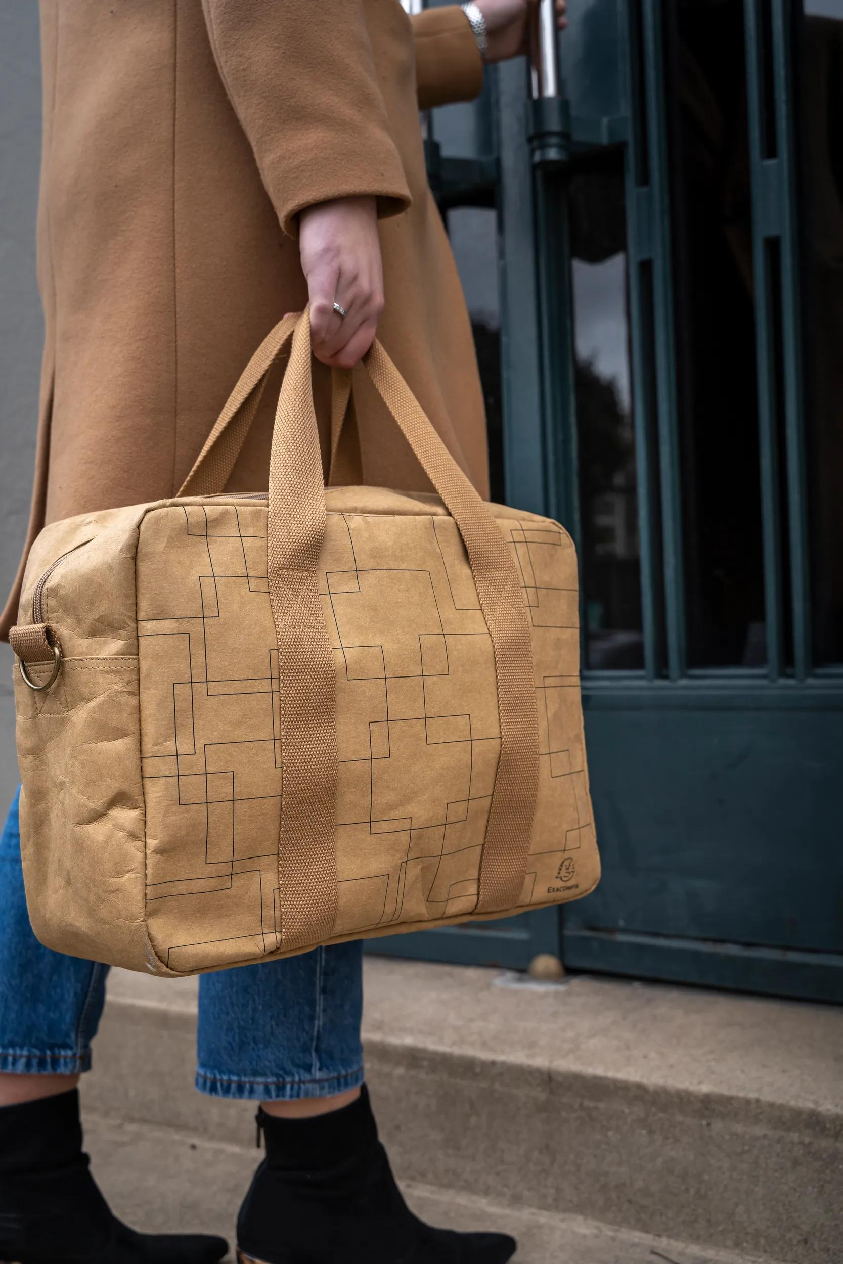 Mujer con abrigo color canela lleva un bolso con estampado geométrico.