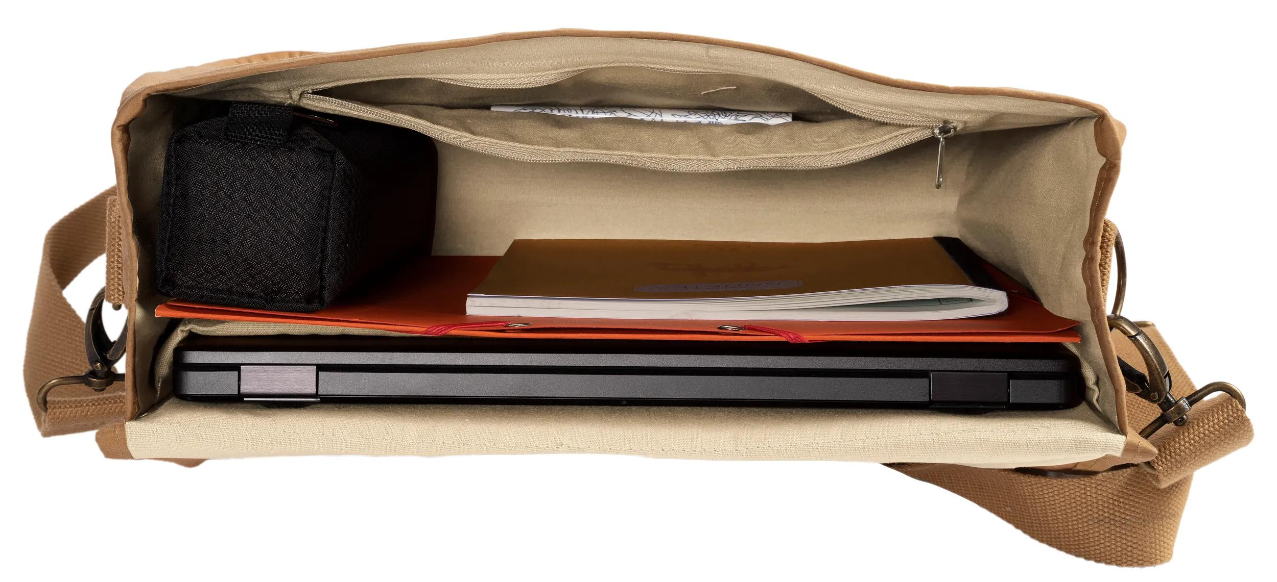 Bolso marrón abierto con portátil, cuaderno y bolsa negra dentro.