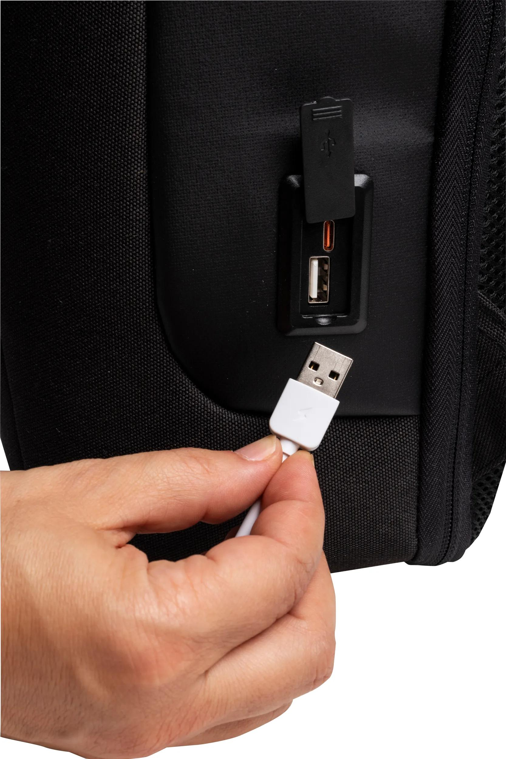 Una mano inserta un cable USB blanco en una mochila negra.