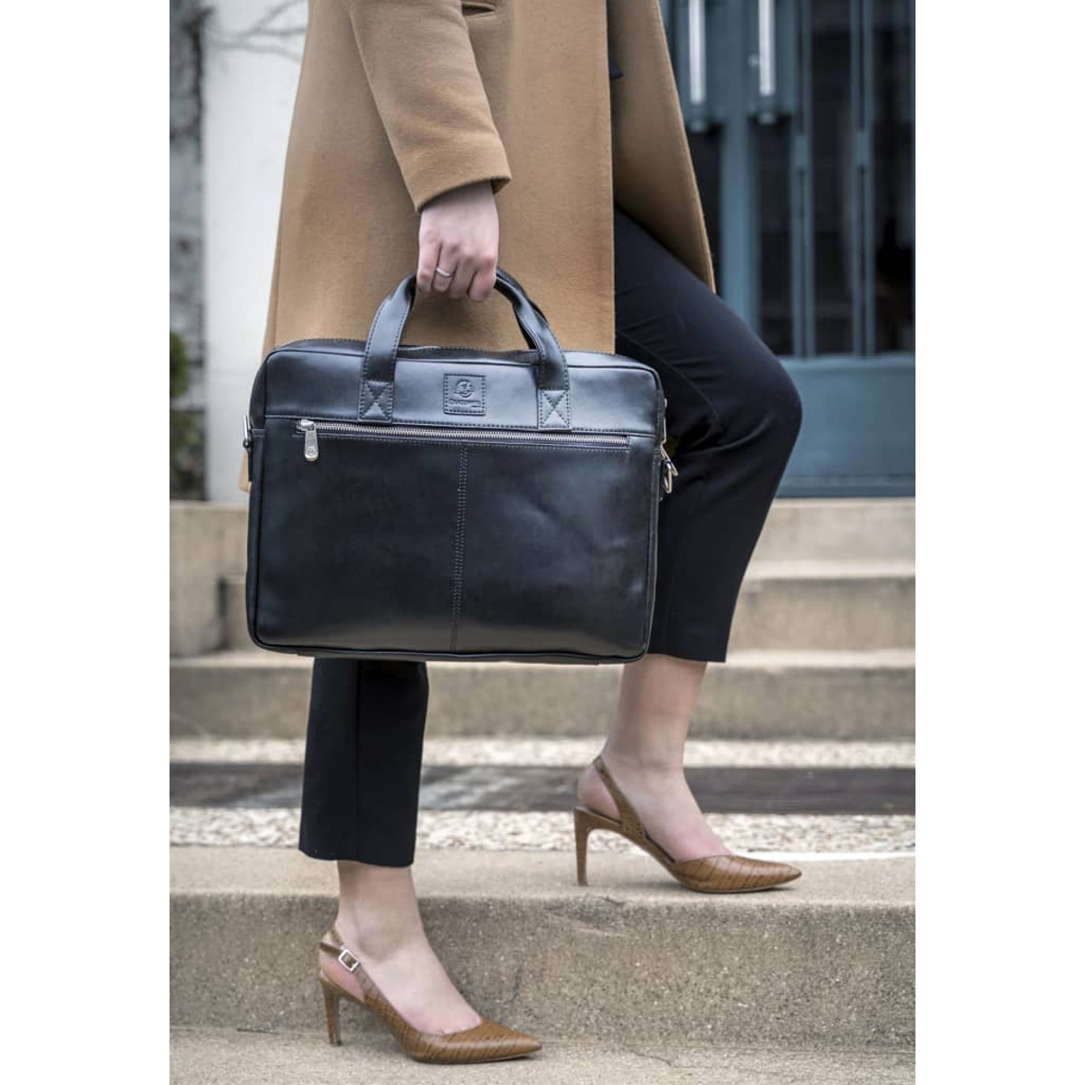 Mujer con abrigo camel lleva bolso negro y salones slingback marrones.