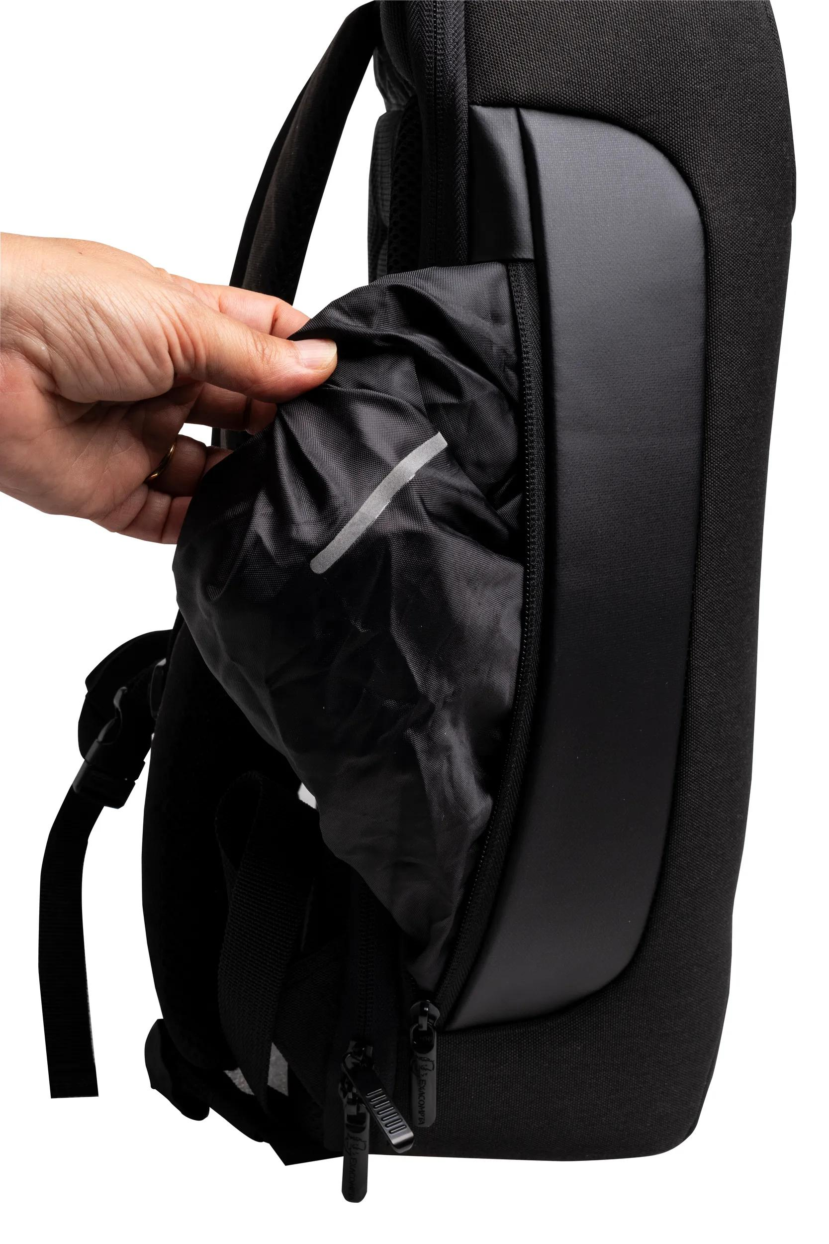 Una mano saca tela negra arrugada de un bolsillo de mochila.