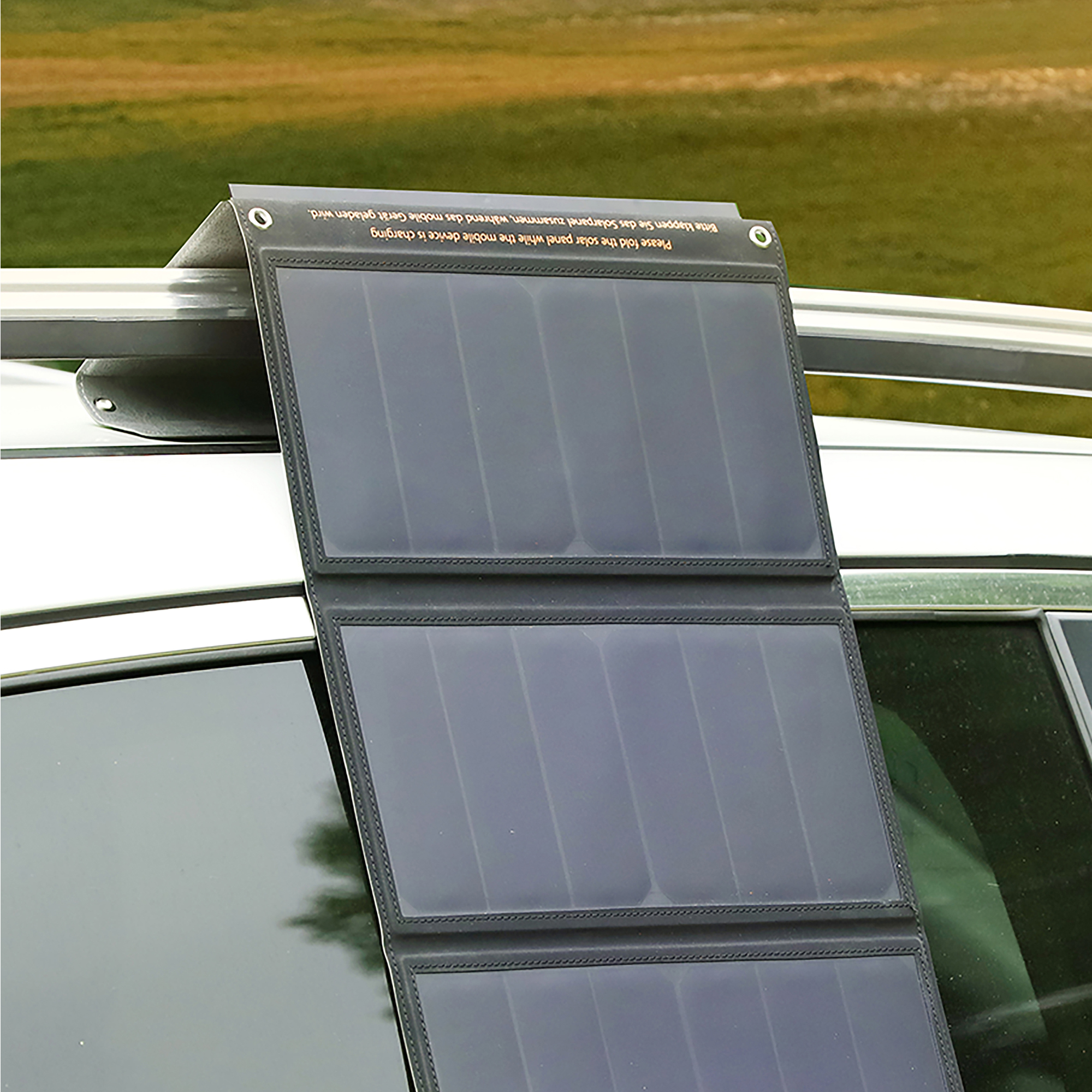 Ein graues Solarpanel ist auf einem Autodach befestigt. Der Hintergrund ist unscharf.