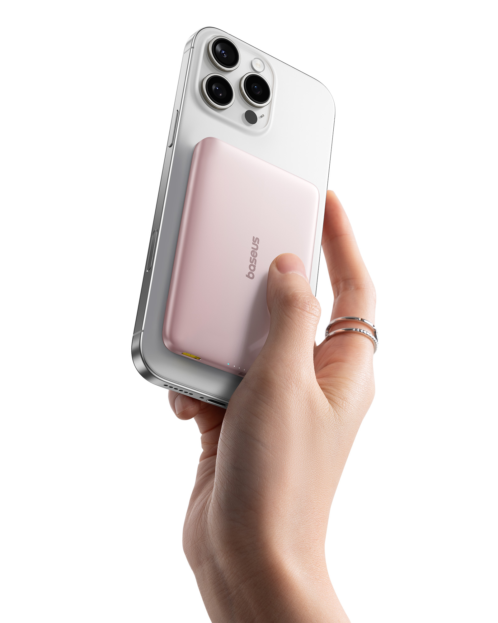 Una mano tiene un iPhone argentato con un power bank rosa attaccato.