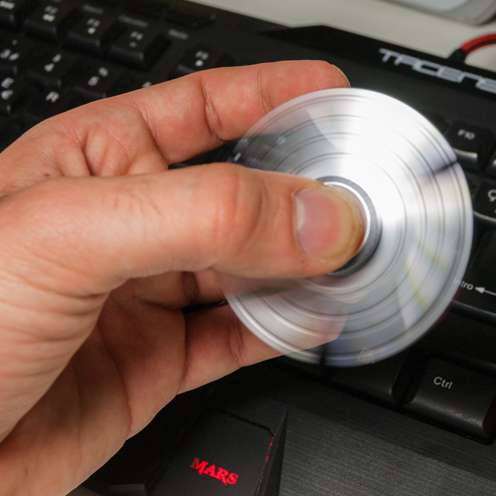 Una mano hace girar un spinner plateado sobre un teclado.