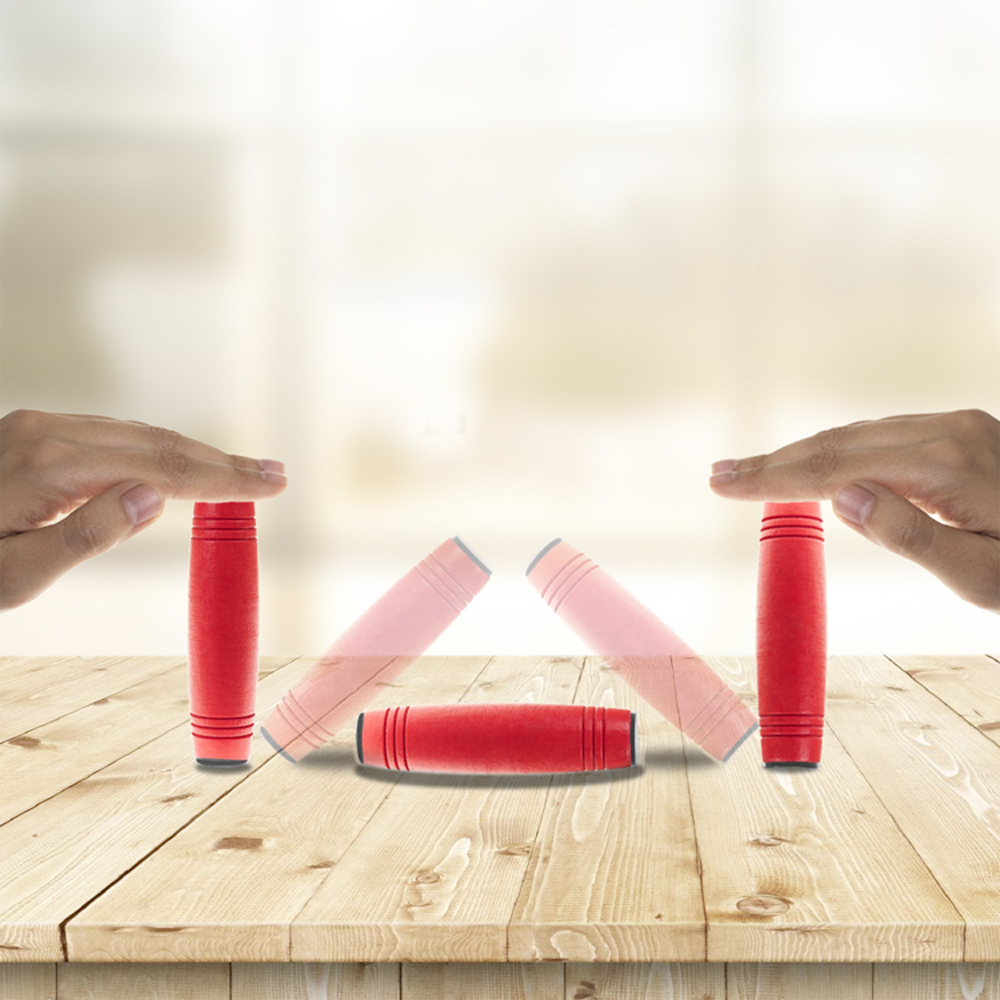 Palos rojos sobre superficie de madera, manos sujetando dos palos verticalmente.
