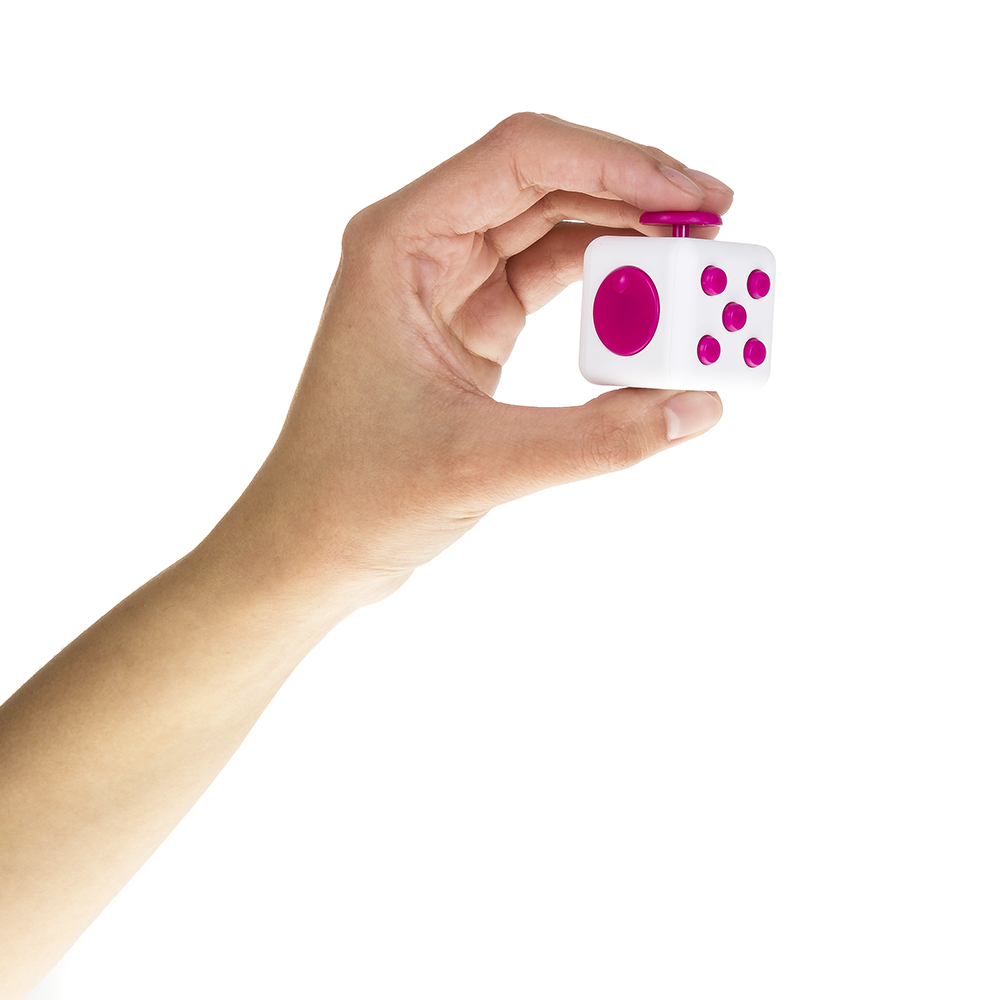 Una mano sostiene un cubo blanco con botones rosas y un joystick rosa.