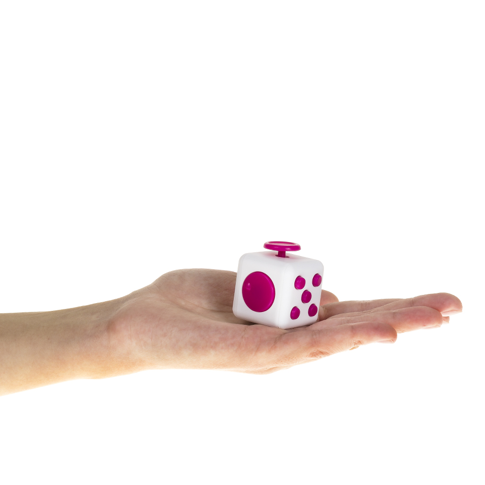Una mano sostiene un cubo blanco con puntos rosas y un botón rosa.
