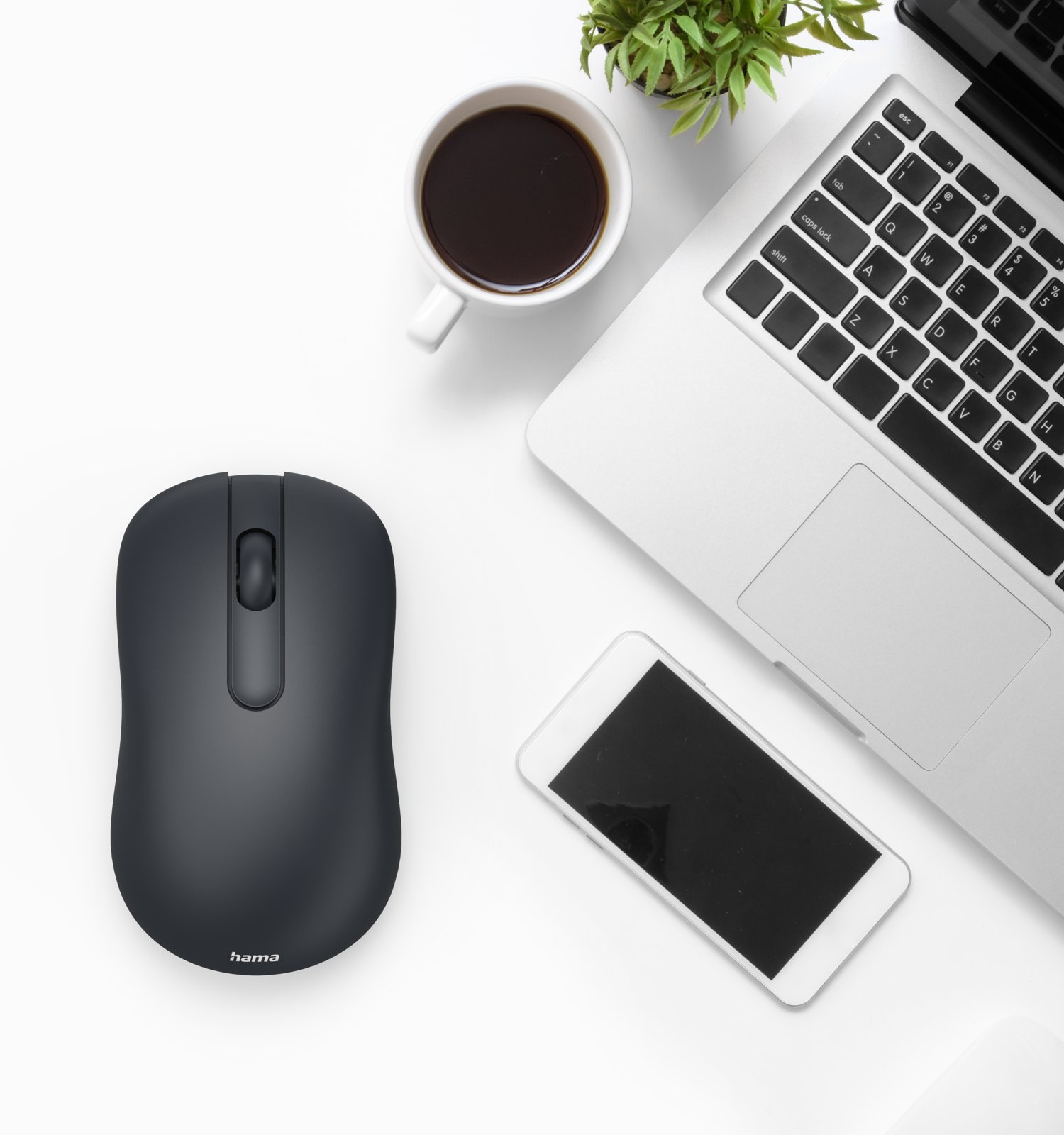 Czarna mysz, laptop, smartfon i kubek kawy na białym biurku.