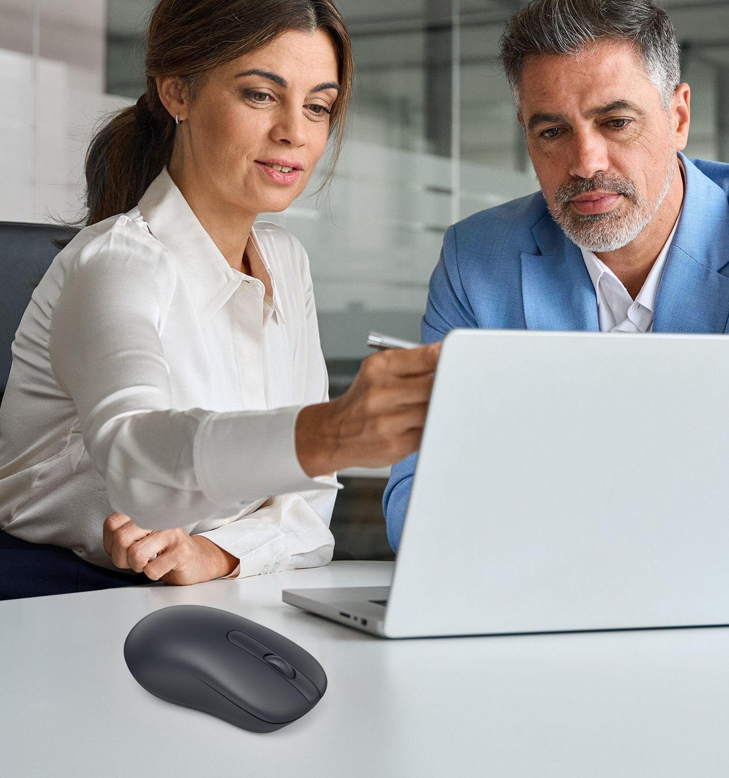 Mężczyzna i kobieta siedzą przy stole, patrząc na laptopa.