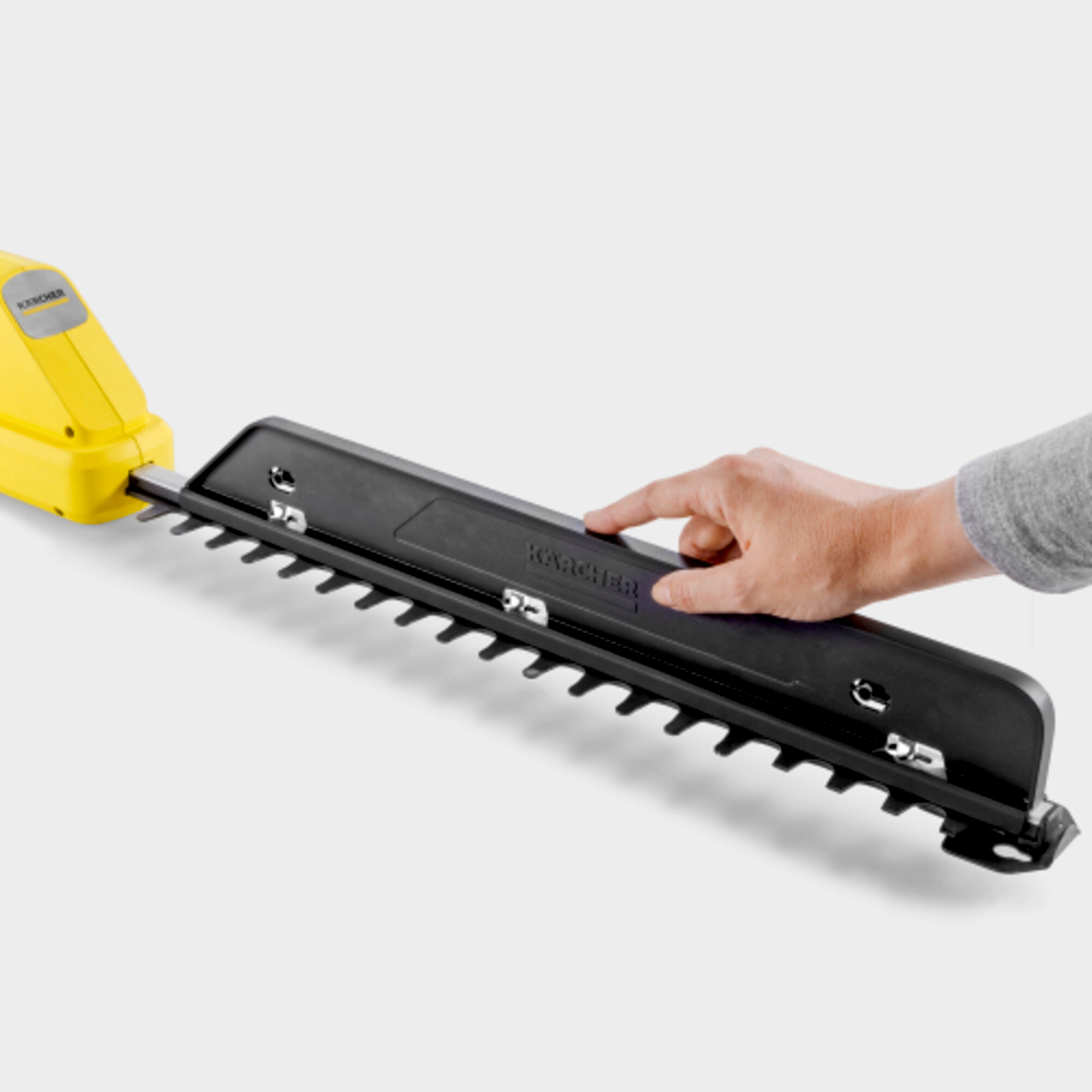 Gelber Heckenscherengriff mit schwarzer Klinge und menschlicher Hand.