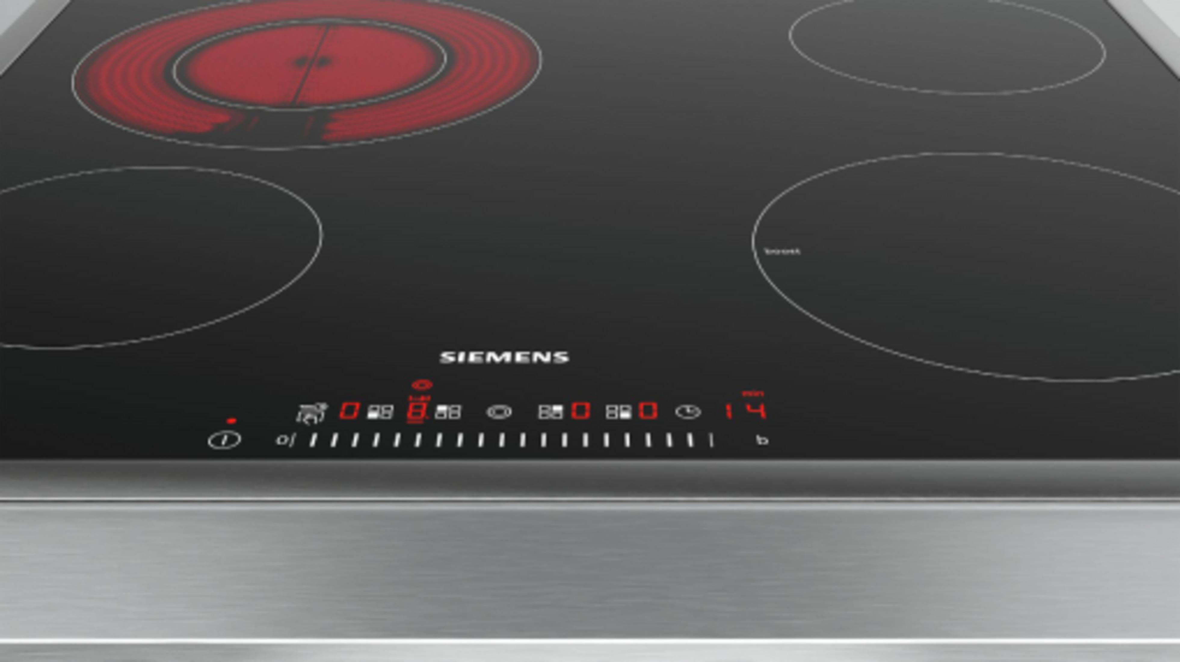 Une plaque à induction Siemens noire avec quatre zones, dont une rougeoyante.