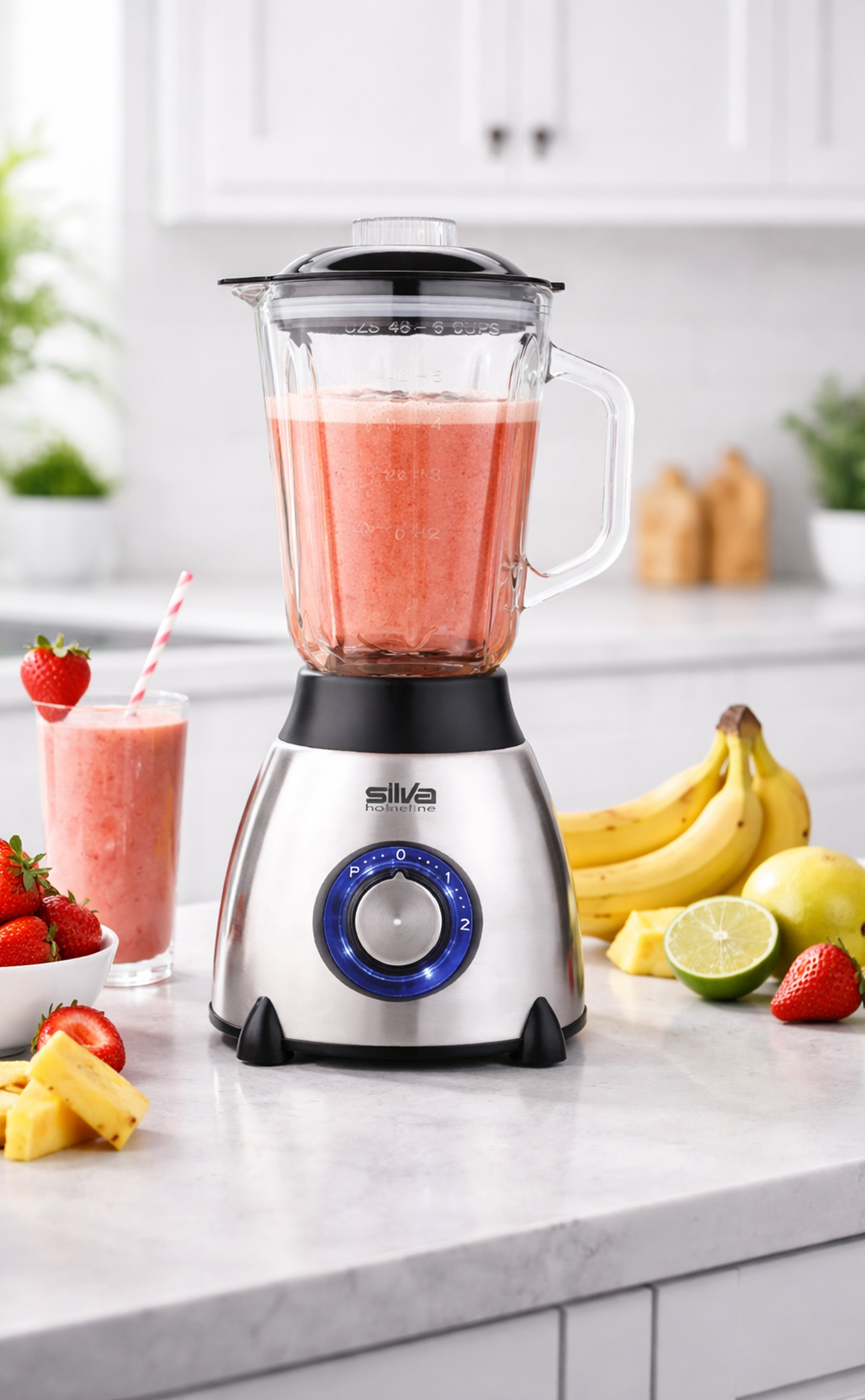 Ein Mixer mit Frucht-Smoothie, daneben Obst wie Erdbeeren, Bananen und Limette.