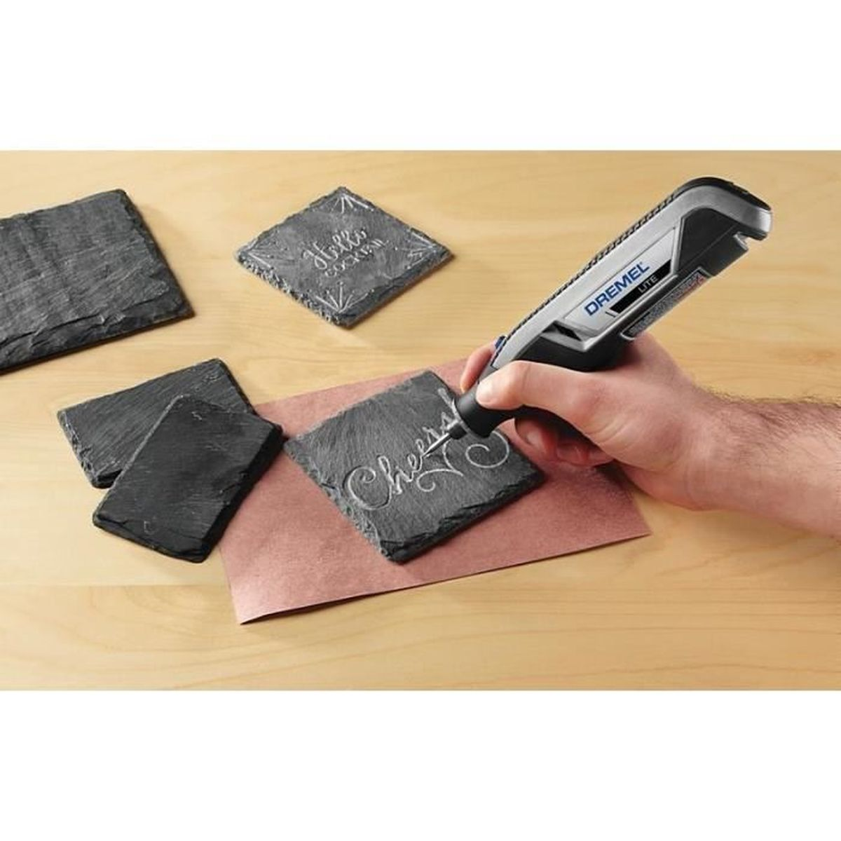 Ein Mann graviert mit einem Dremel-Werkzeug auf einen Steinuntersetzer.