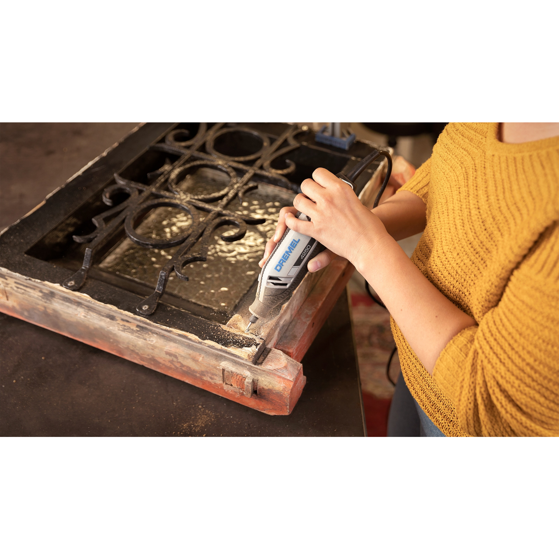 Persona leviga un vecchio telaio di finestra in legno con attrezzo Dremel.