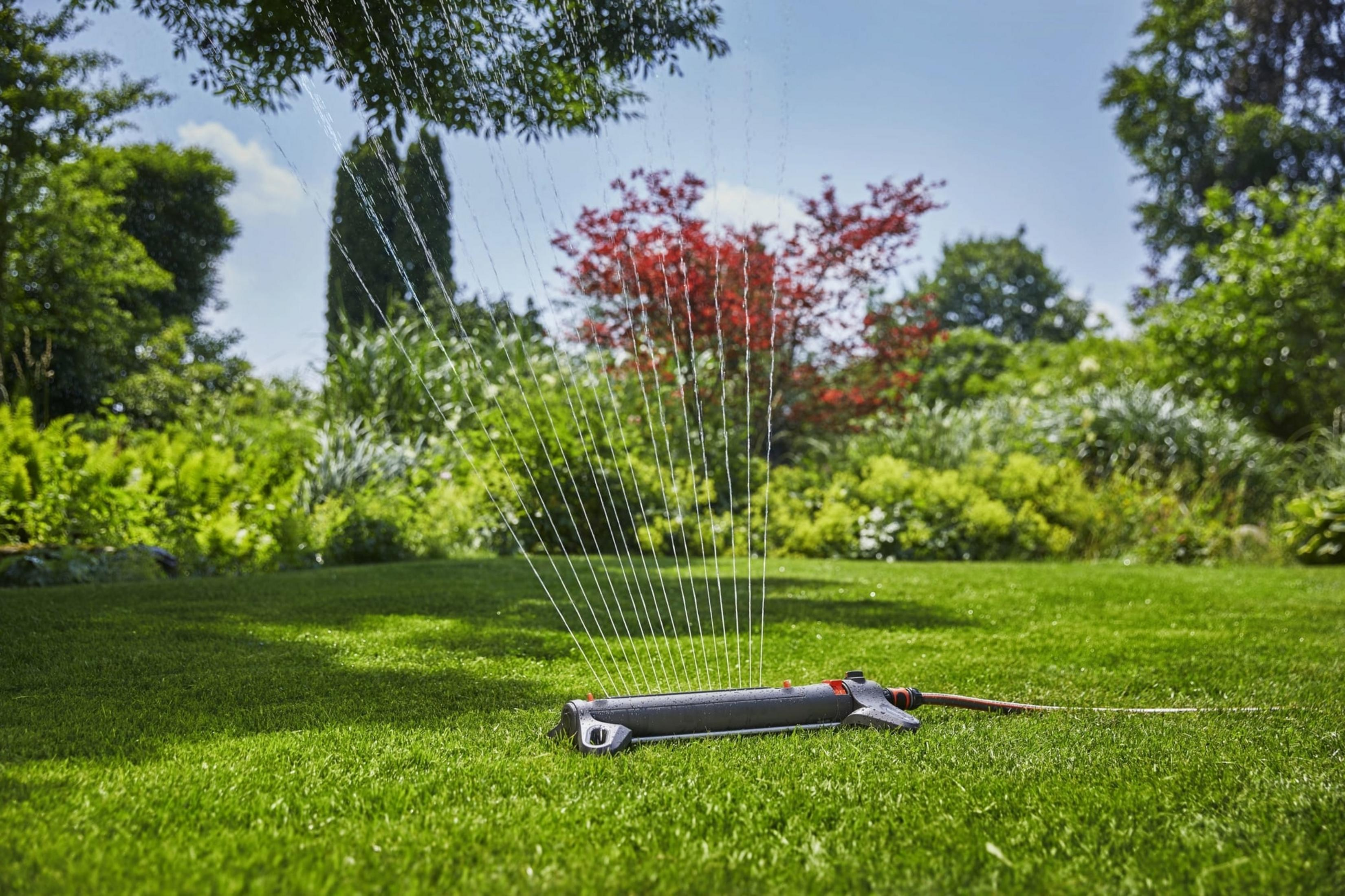 Un irrigatore da prato annaffia un prato verde in un giardino.