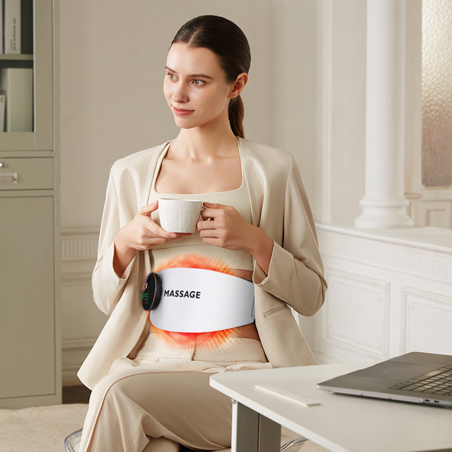 Una mujer sentada con una taza y un masajeador en la cintura.
