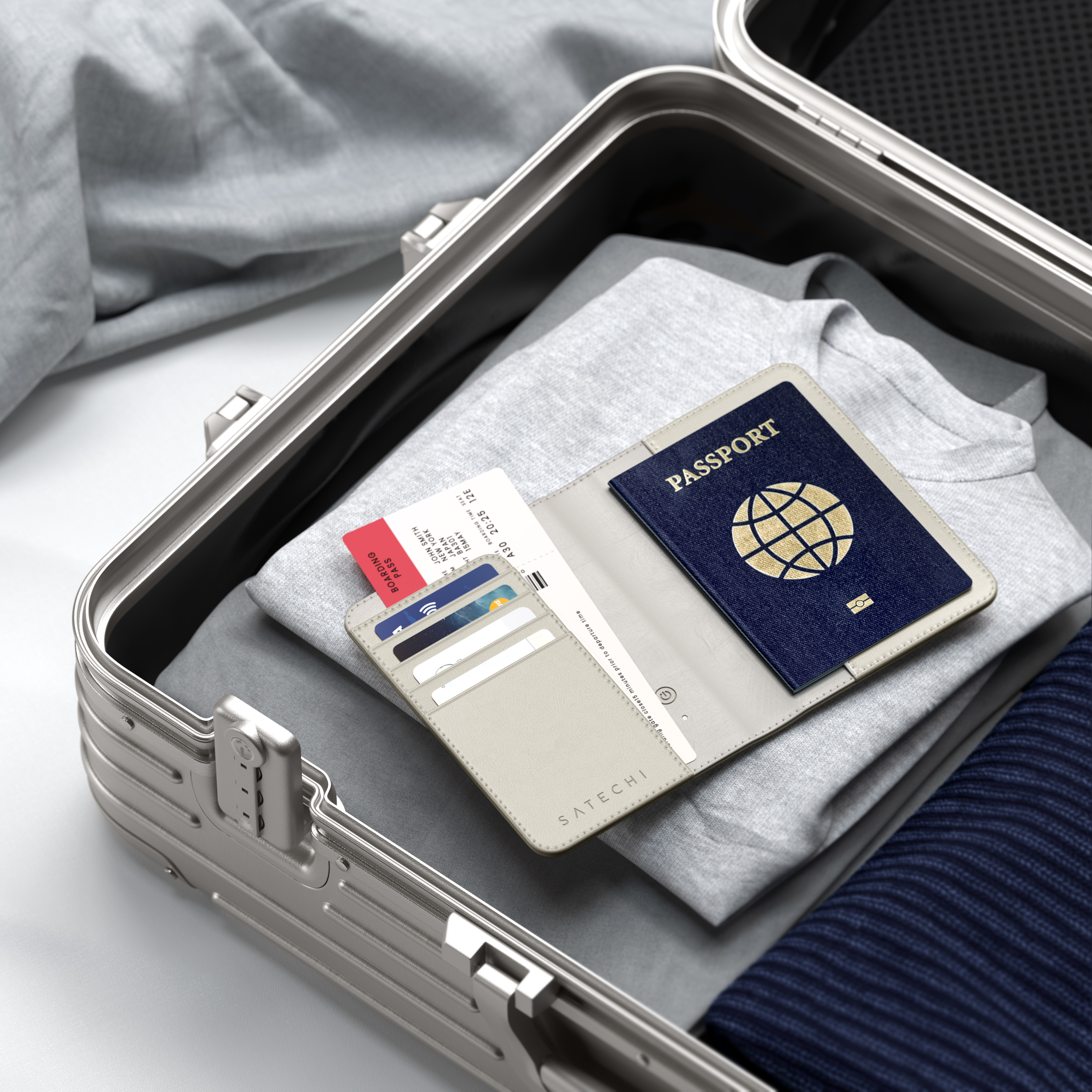 Una valigia argentata è piena di vestiti, passaporto e carte d'imbarco.