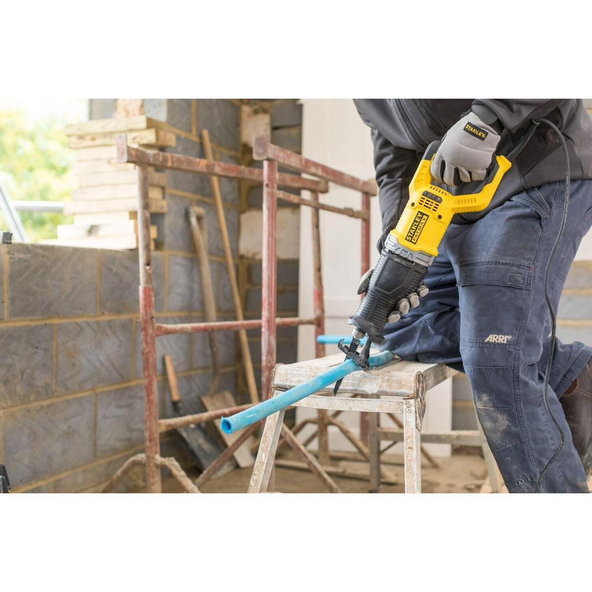 Man cuts pipe with reciprocating saw on a construction site.