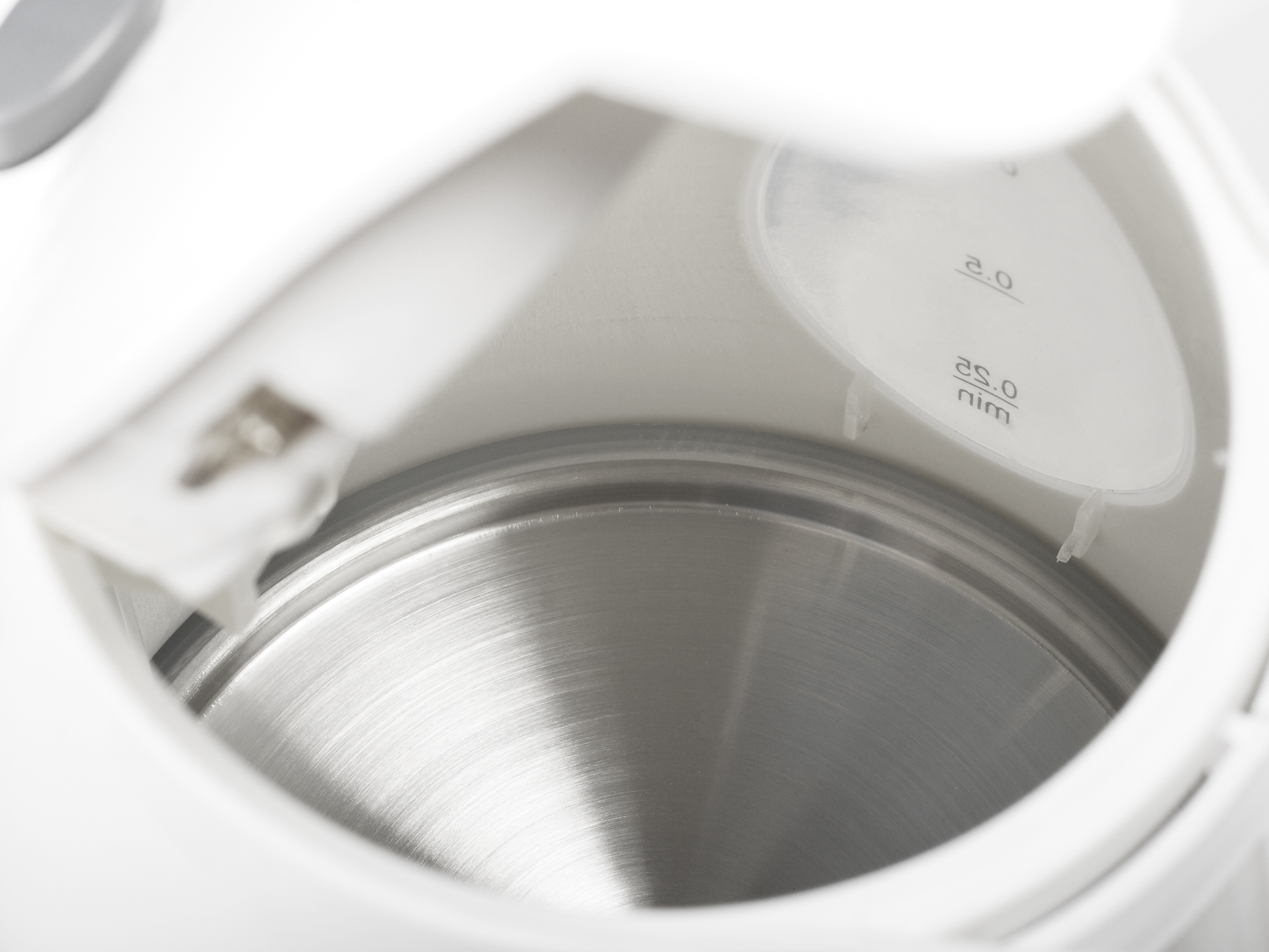 Nahaufnahme des Innenraums eines weißen Wasserkochers aus Edelstahl mit Füllstandsanzeigen.