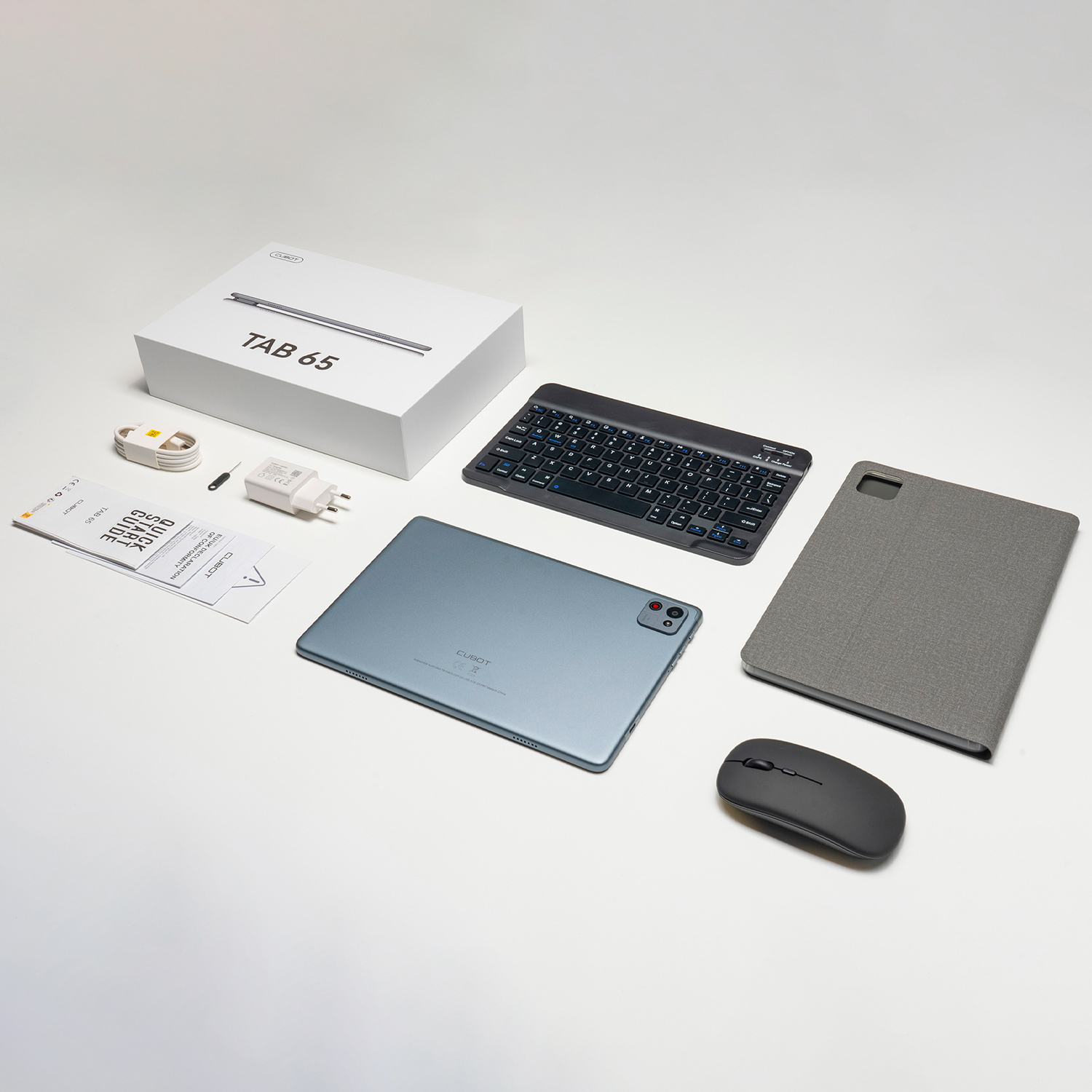 Tablet, klawiatura, mysz, ładowarka i instrukcje na białej powierzchni.