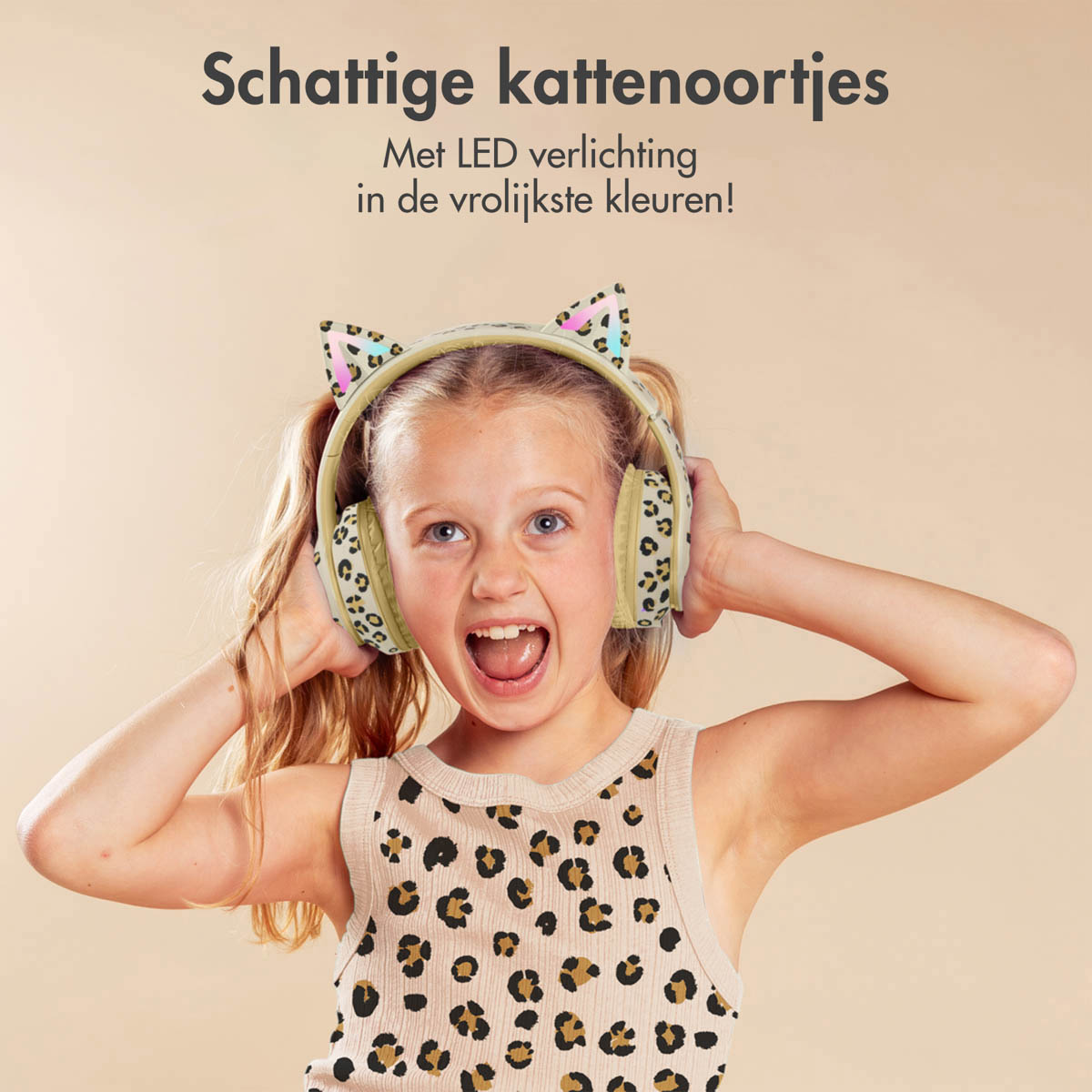 Girl with cat ear headphones, laughing with hands on ears. Leopard print shirt.