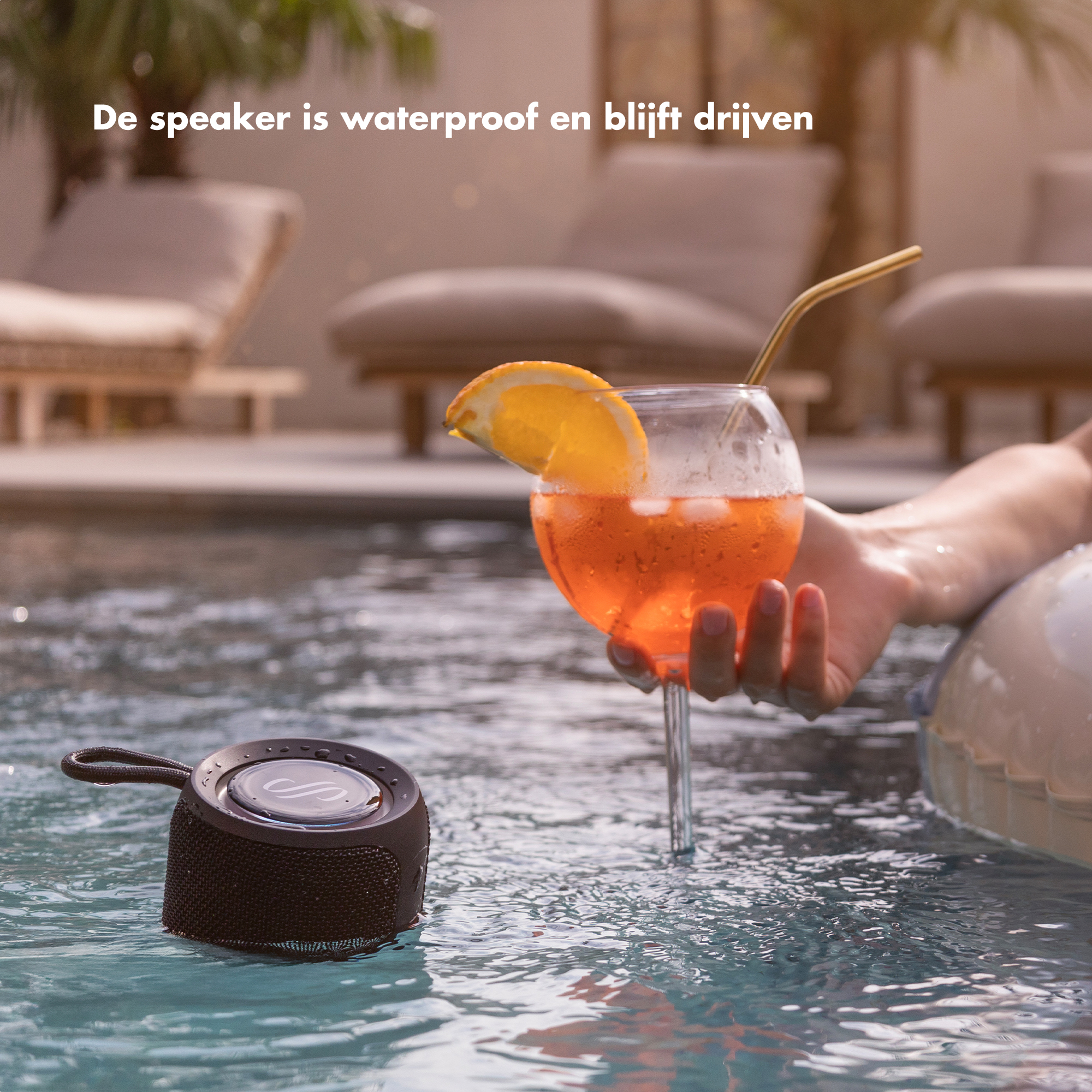 Een waterdichte speaker drijft in een zwembad naast een drankje.