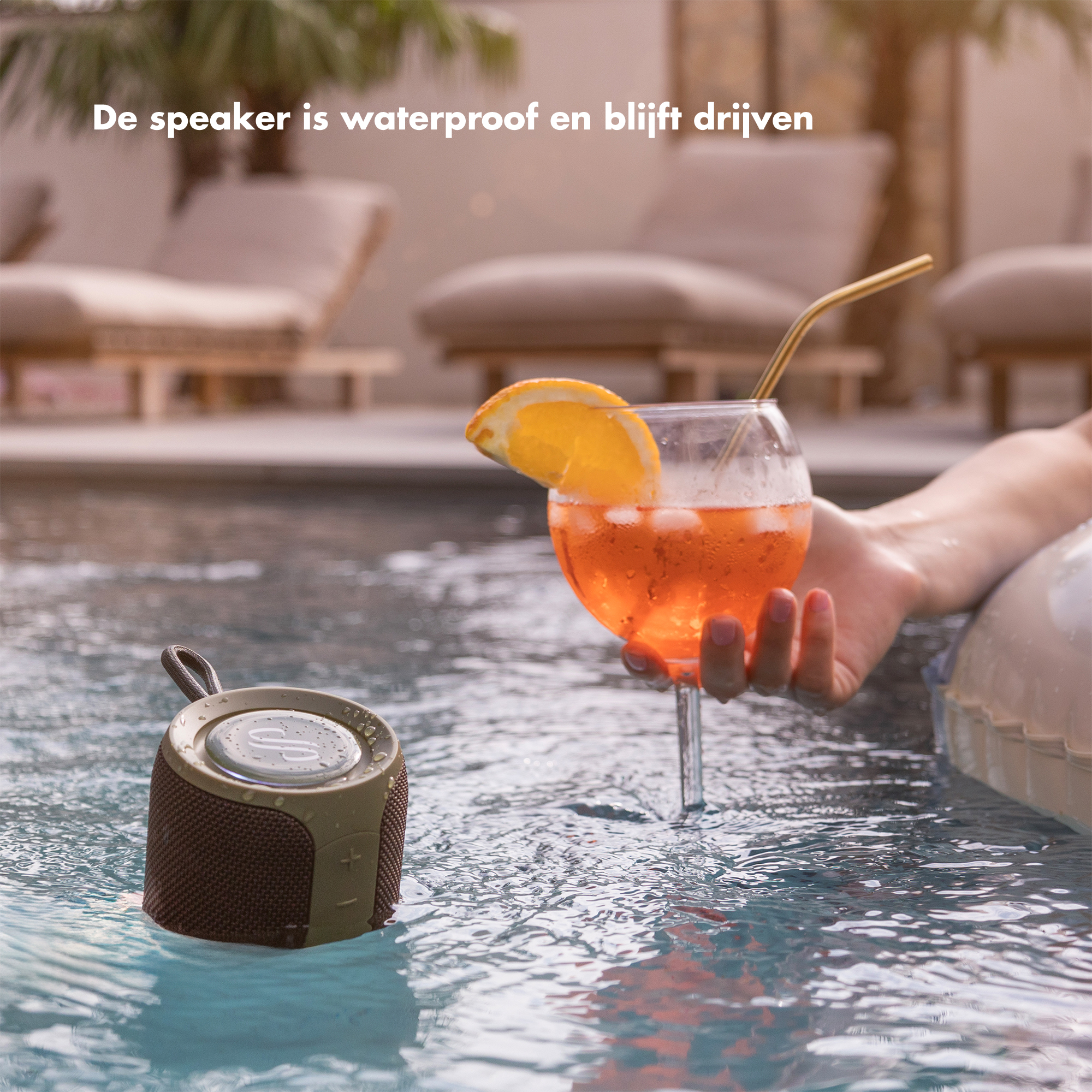 Een waterdichte speaker drijft in een zwembad naast een drankje.
