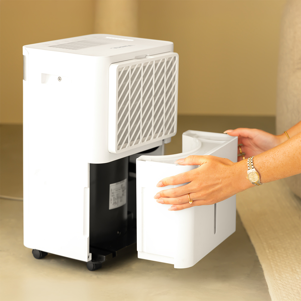 A person removes a white container from a white dehumidifier.